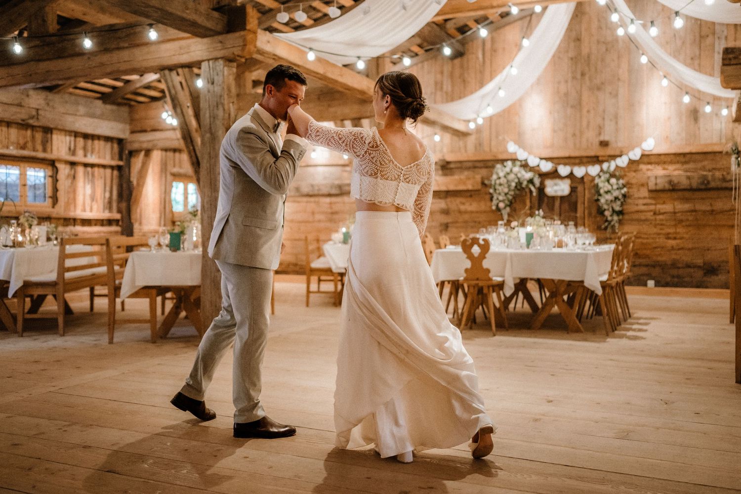 Romantic dance sequence in rustic barn venue with string lights and wooden floors.