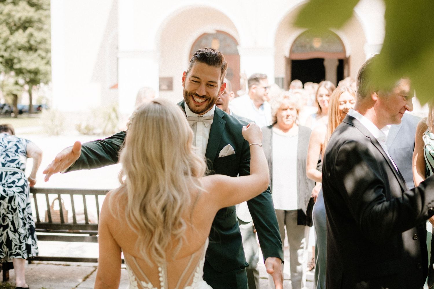 A joyful moment between newlyweds dancing at an outdoor wedding reception with guests looking on.
