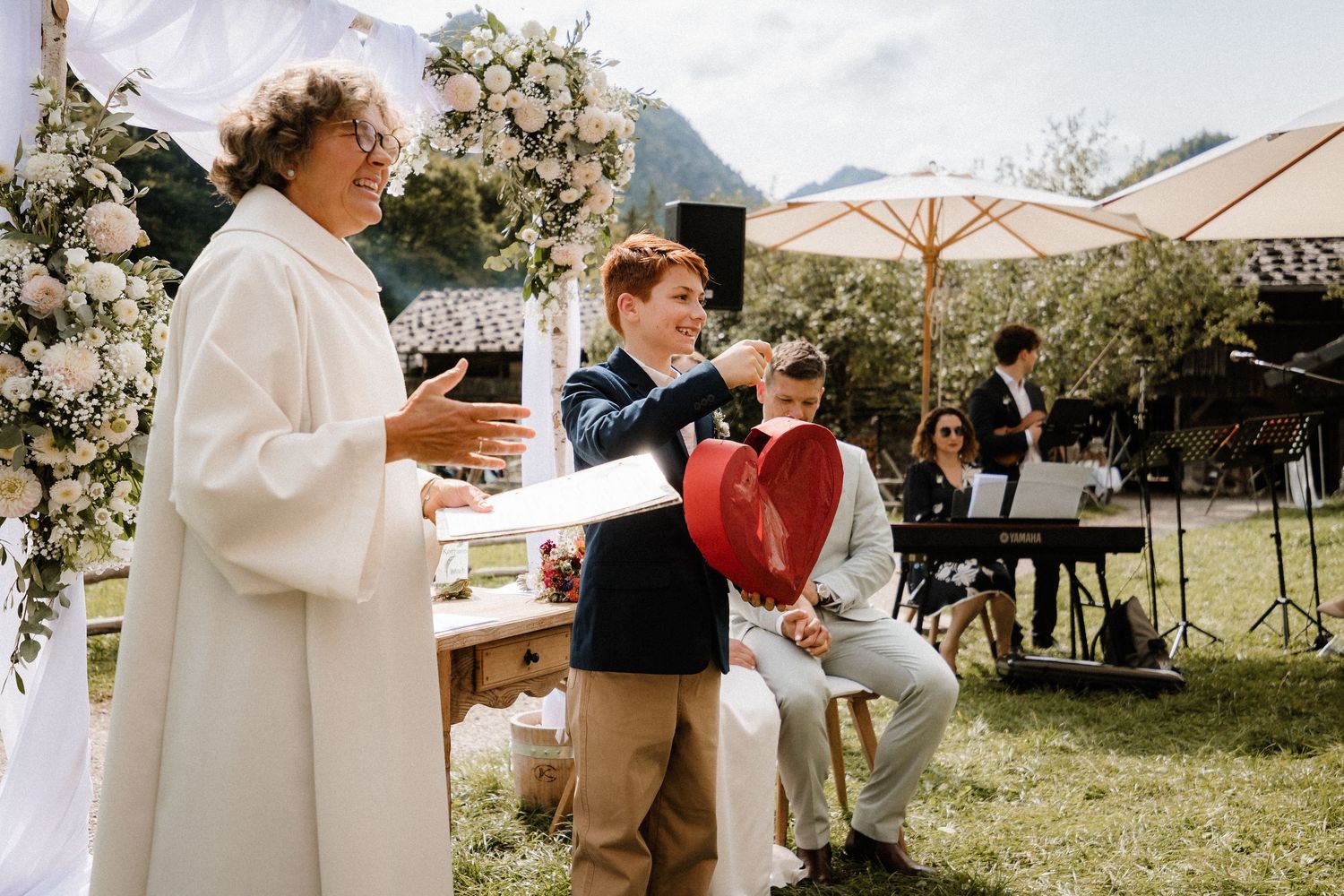 Outdoor wedding ceremony with guests and white floral arch.