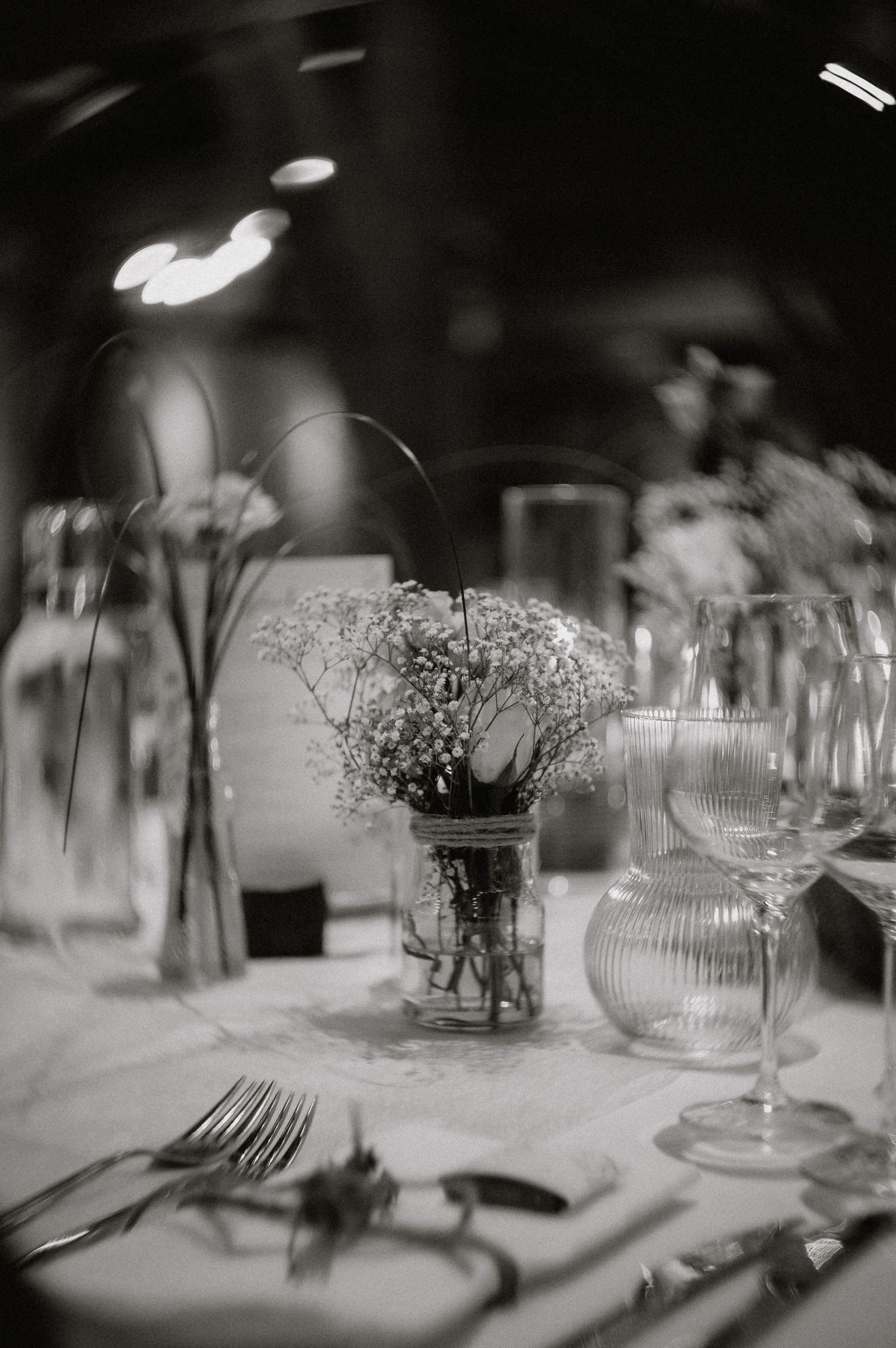 Black and white table setting with delicate glassware and baby's breath centerpieces.
