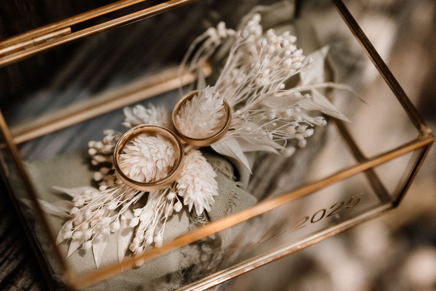 Wedding rings displayed in an elegant glass box with delicate details.
