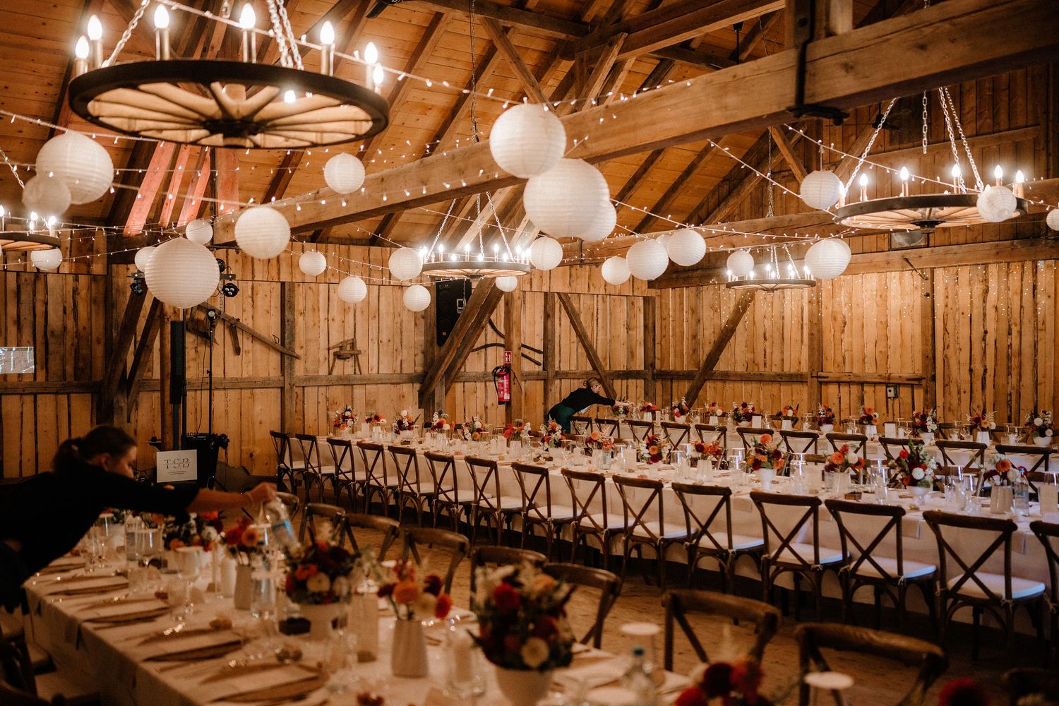 Rustic barn wedding reception venue with warm lighting, wooden beams, and elegant table settings in a romantic atmosphere.