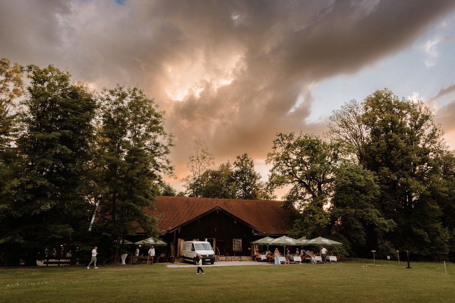Dramatic storm clouds gather over a countryside wedding venue at sunset.