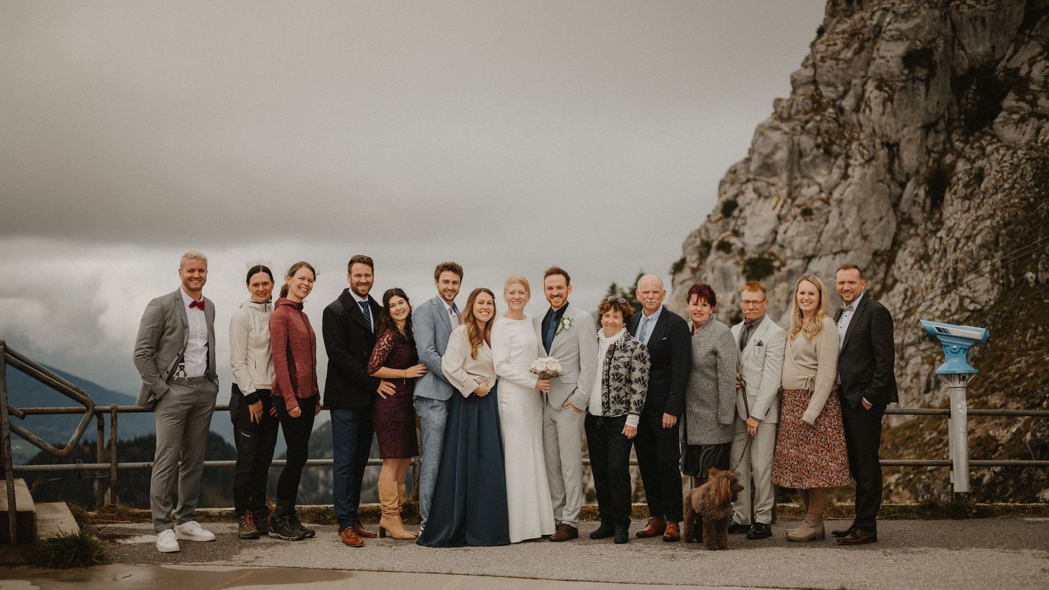 Wedding party gathered on a mountain overlook with dramatic cliffs in the background.