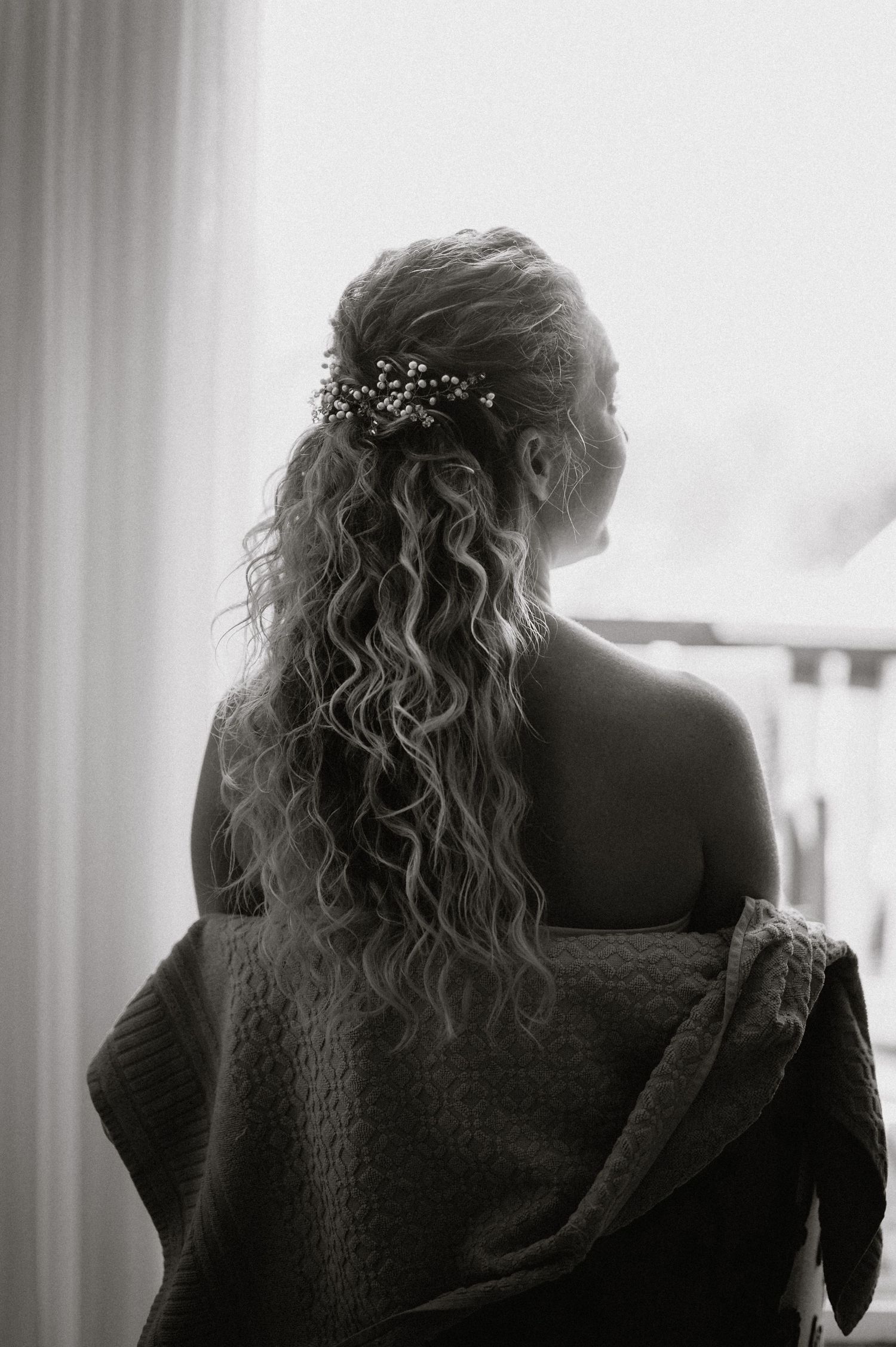 Artistic black and white portrait showing textured fabric and curled hair.