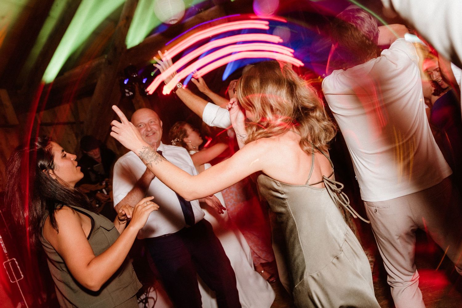 Wedding reception dance floor illuminated with vibrant pink and purple lighting.