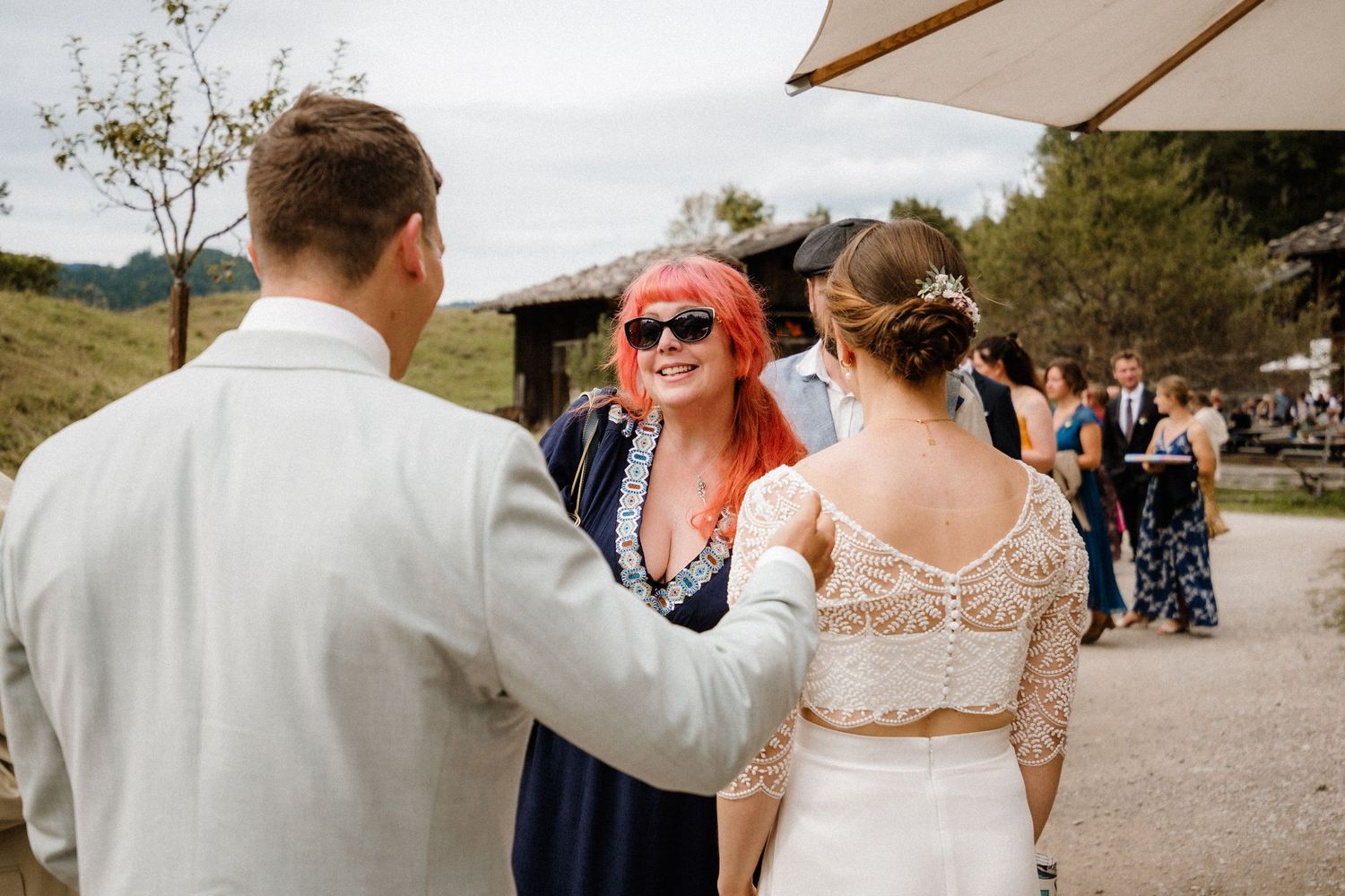 Guests celebrate at an outdoor wedding reception with mountains in the background.