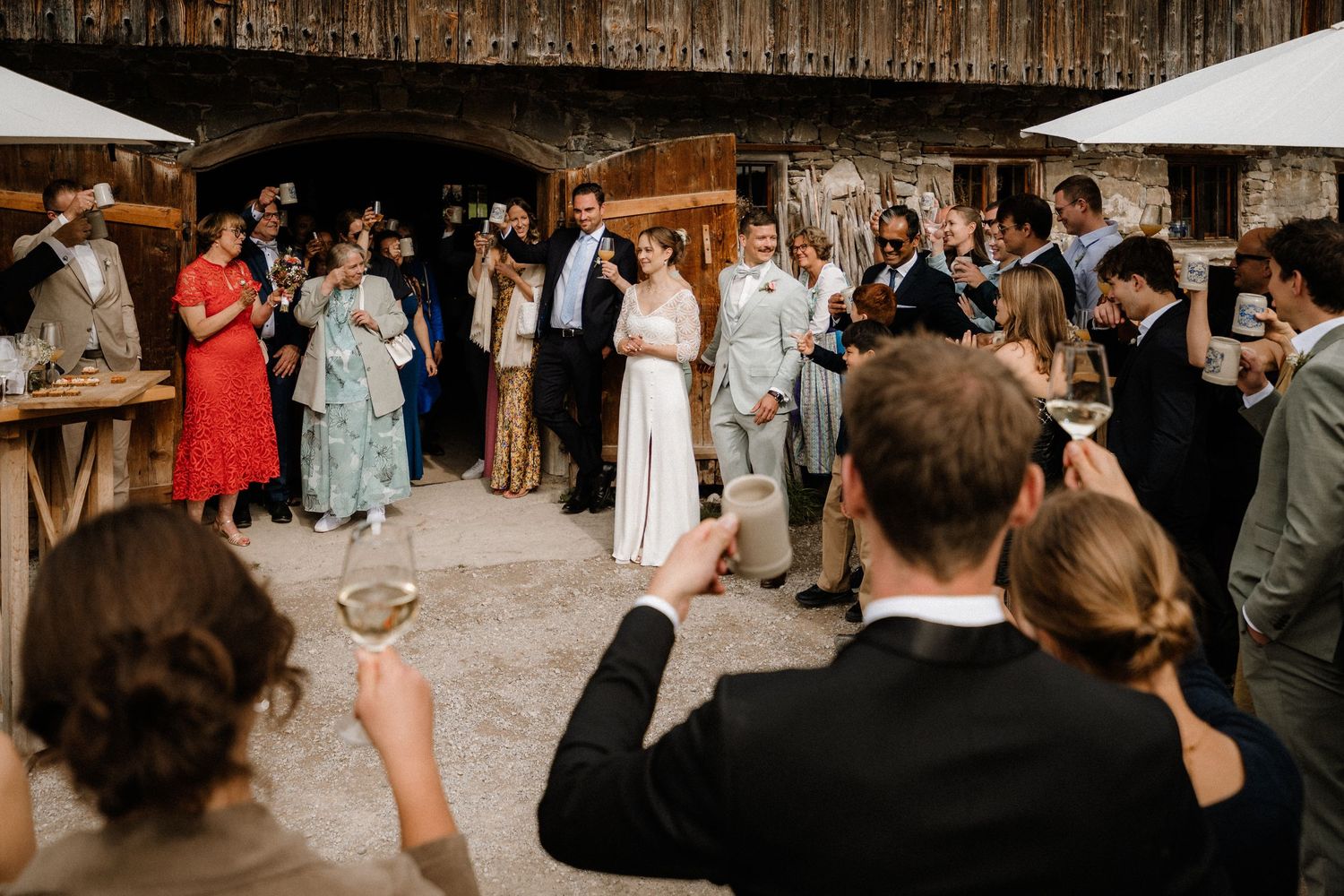 Guests dance and mingle in a rustic barn setting during a wedding reception.