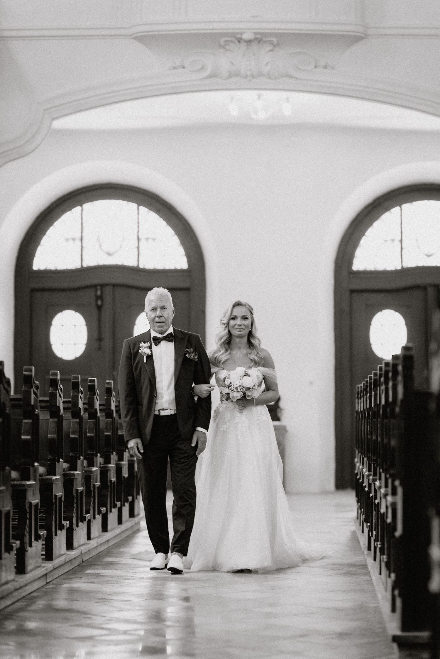 A black and white sequence of wedding processional photos in a traditional church aisle.