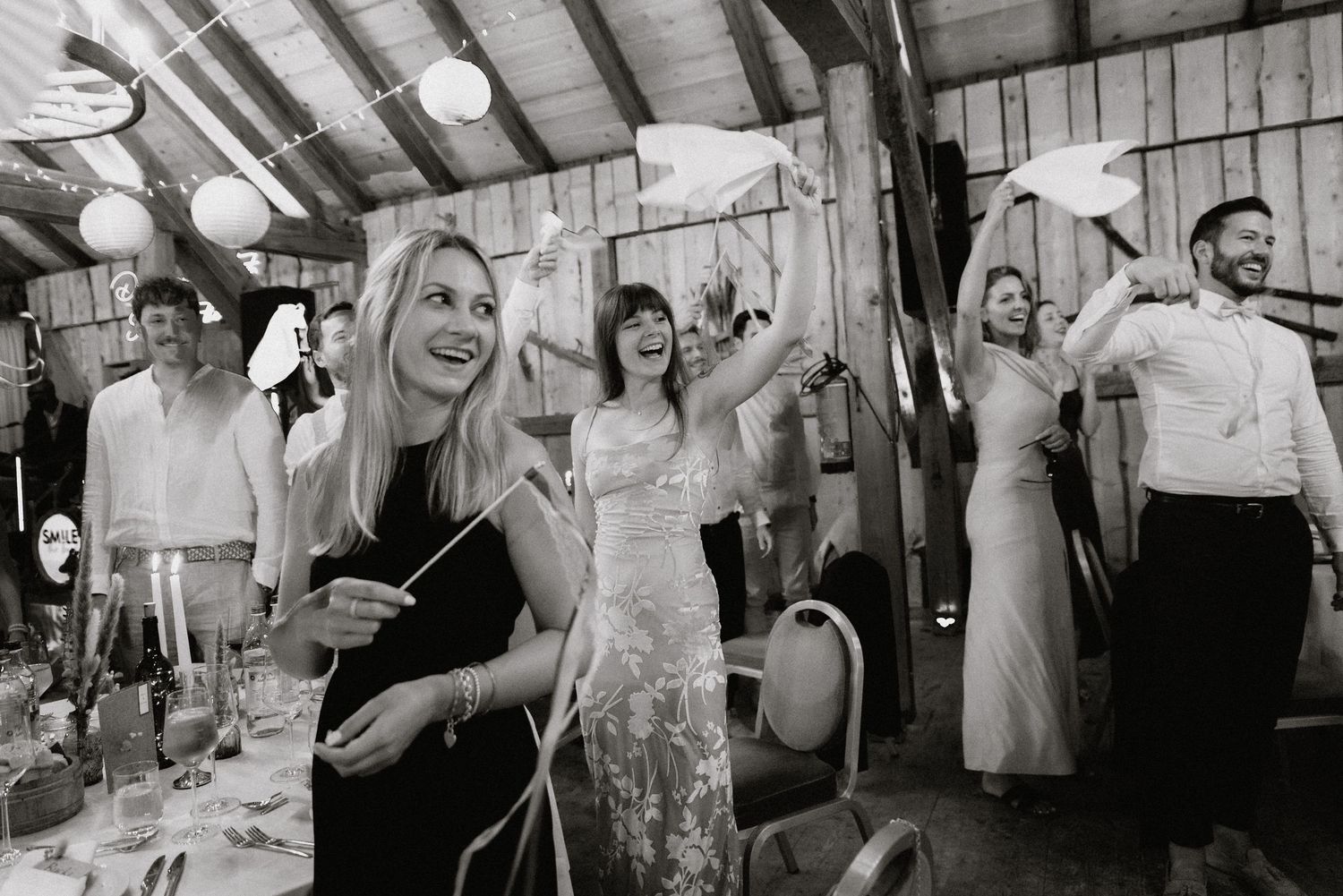 Wedding celebration with guests dancing in rustic barn setting.