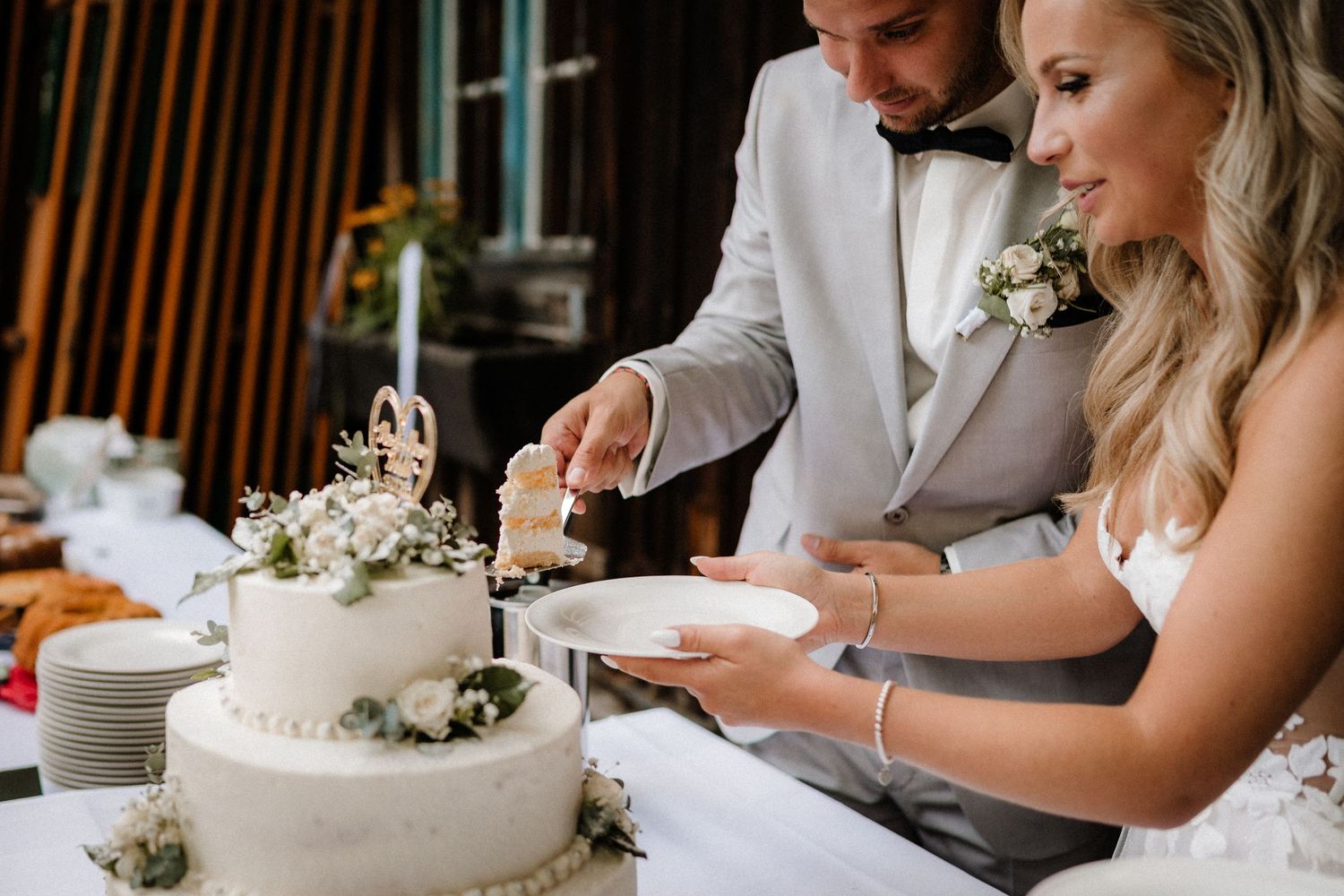 A couple shares their wedding cake cutting moment at an elegantly set reception table.