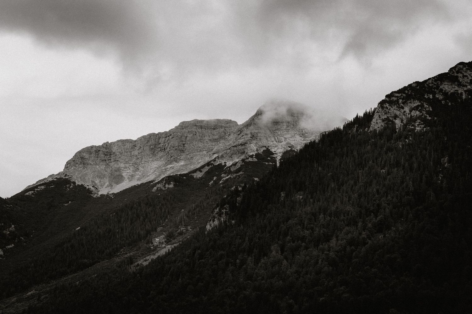 Stimmungsvoller schwarz-weißer Berggipfel in Nebelwolken gehüllt. Von Dama Fotografie Bad Tölz