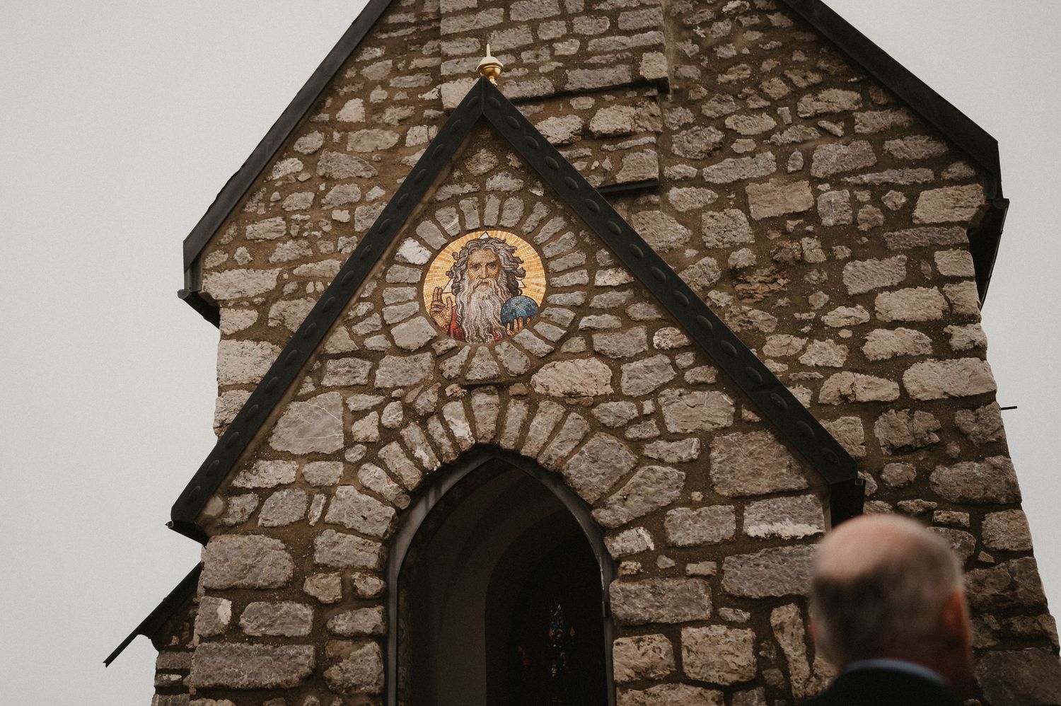 Stone chapel exterior with an arched entrance and circular window detail.