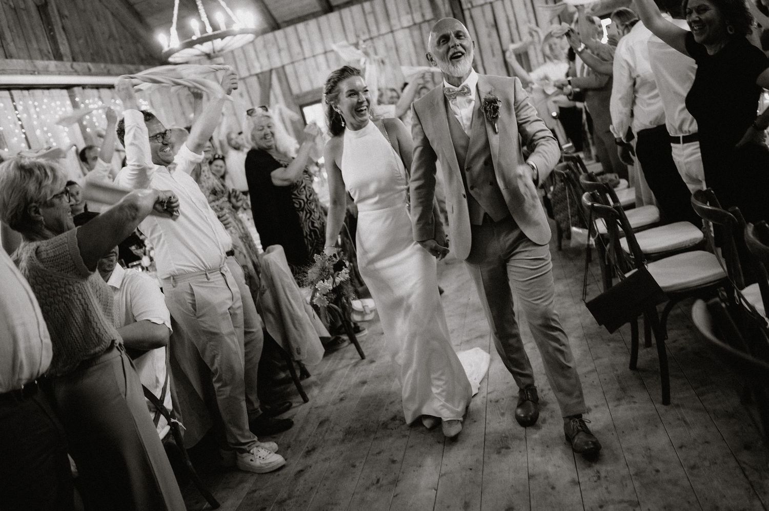 Wedding guests dance and celebrate on a rustic wooden dance floor during an evening reception.