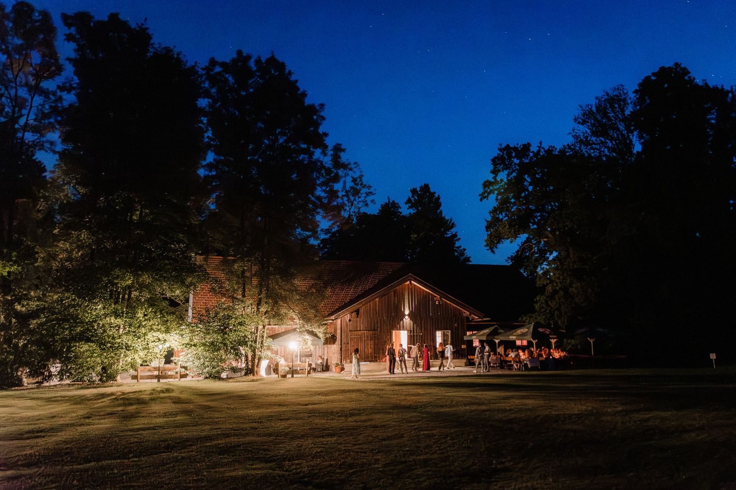 Nighttime exterior view of a rustic barn venue with ambient lighting.