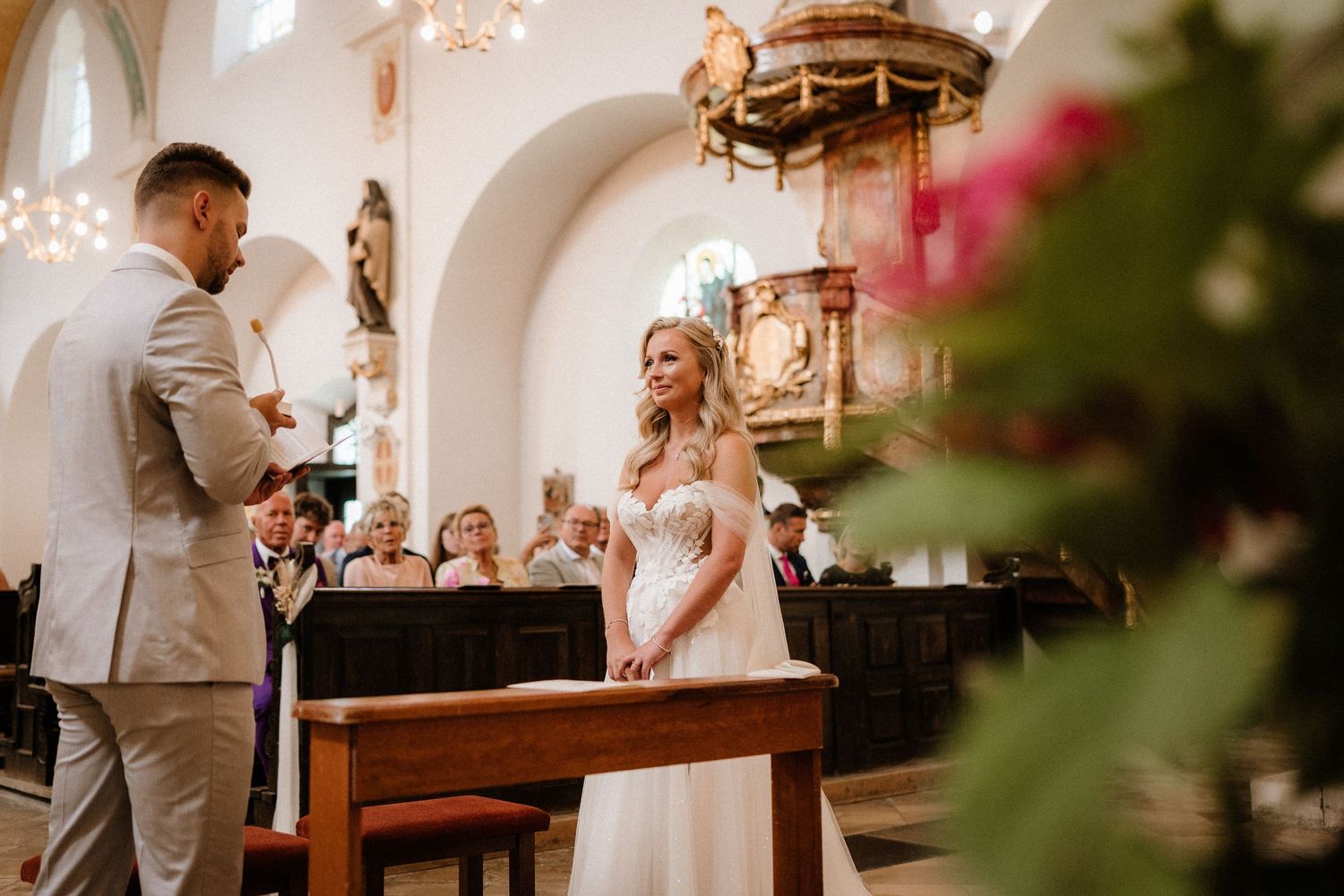 Intimate church wedding ceremony with soft lighting and floral decorations.