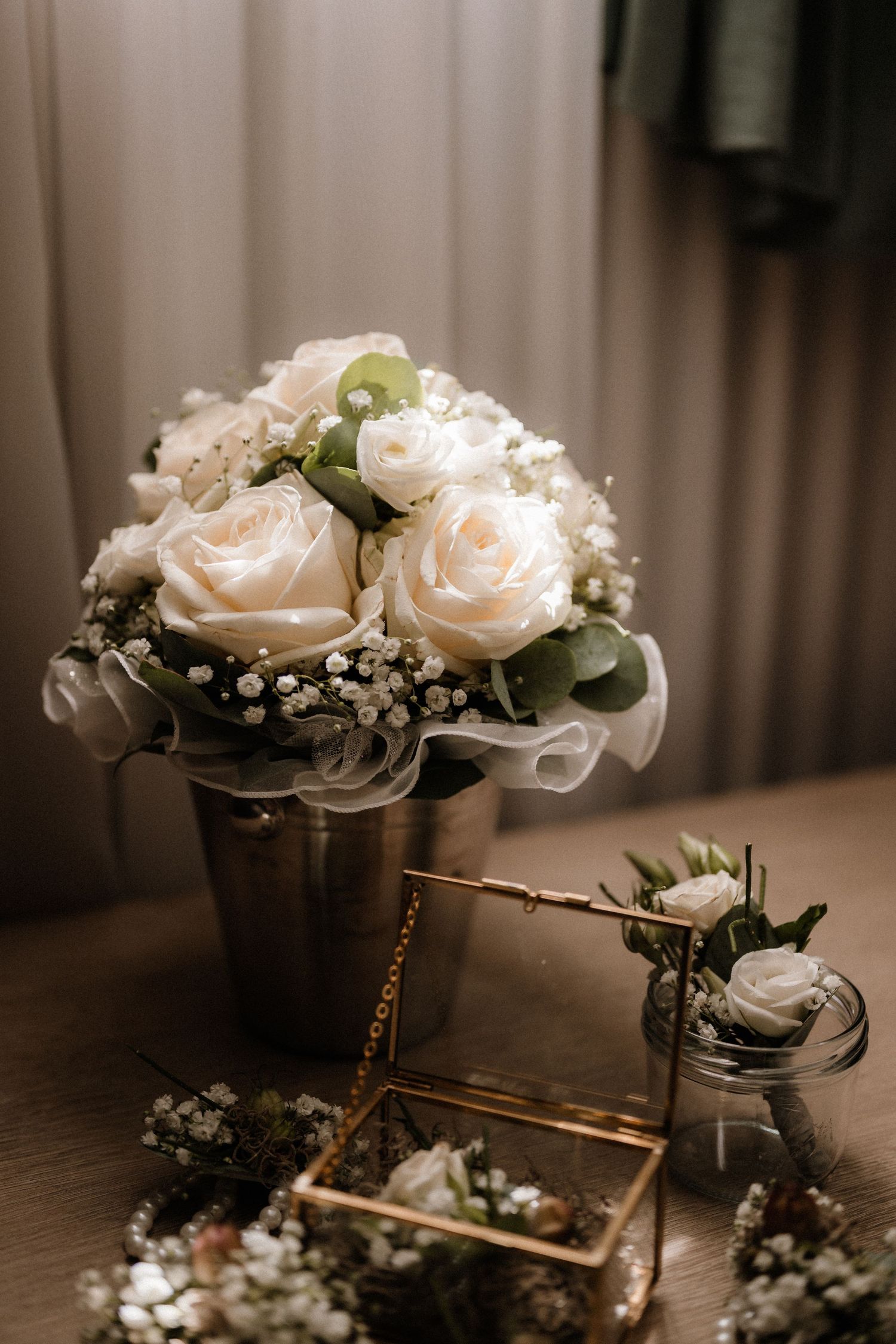 Elegant white rose and baby's breath wedding centerpiece arrangement in a silver vase.