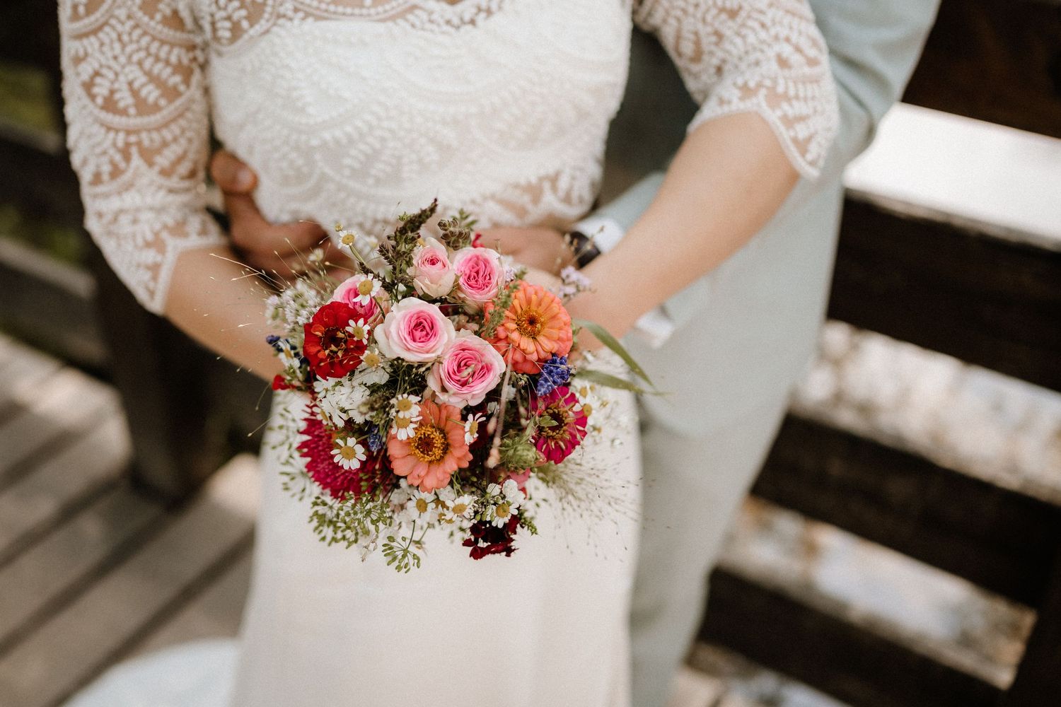A close-up of a colorful bridal bouquet with red, pink and orange flowers.