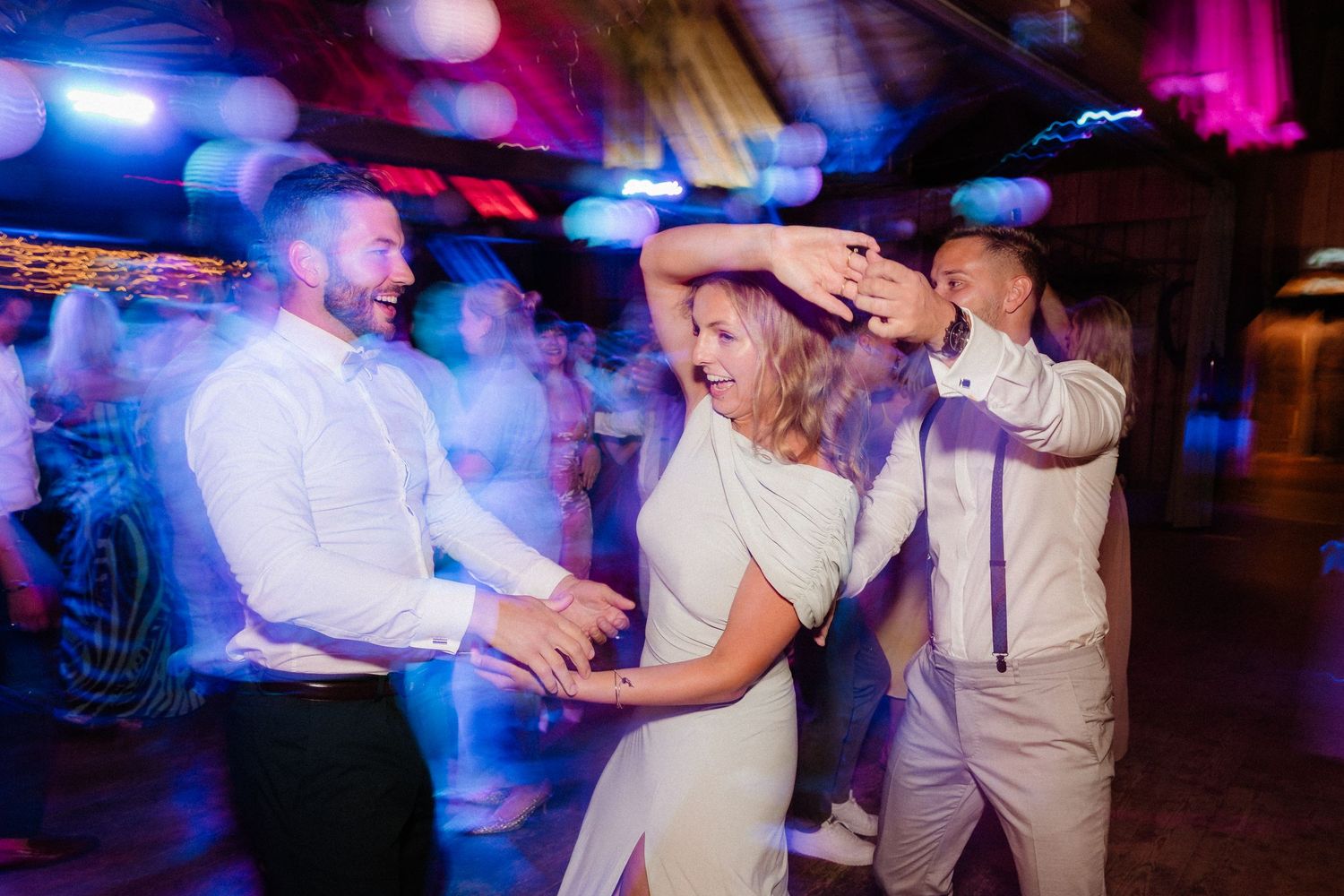 Wedding reception dance floor with blue and pink lighting creating a vibrant party atmosphere.