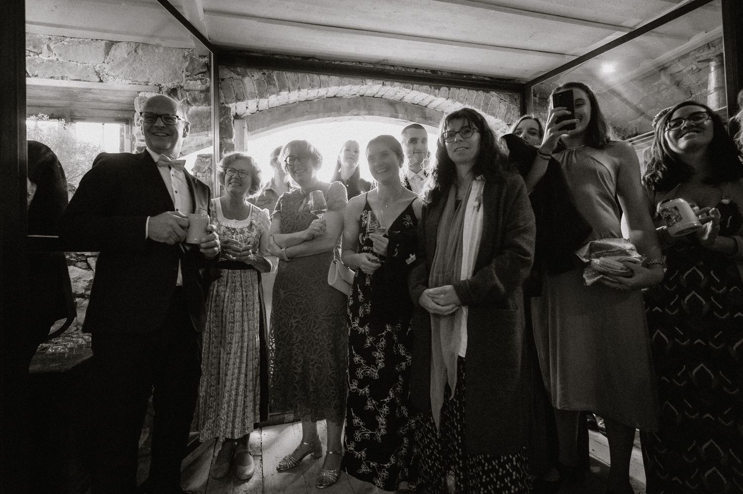 Black and white panoramic photo of wedding guests gathered at a reception venue.