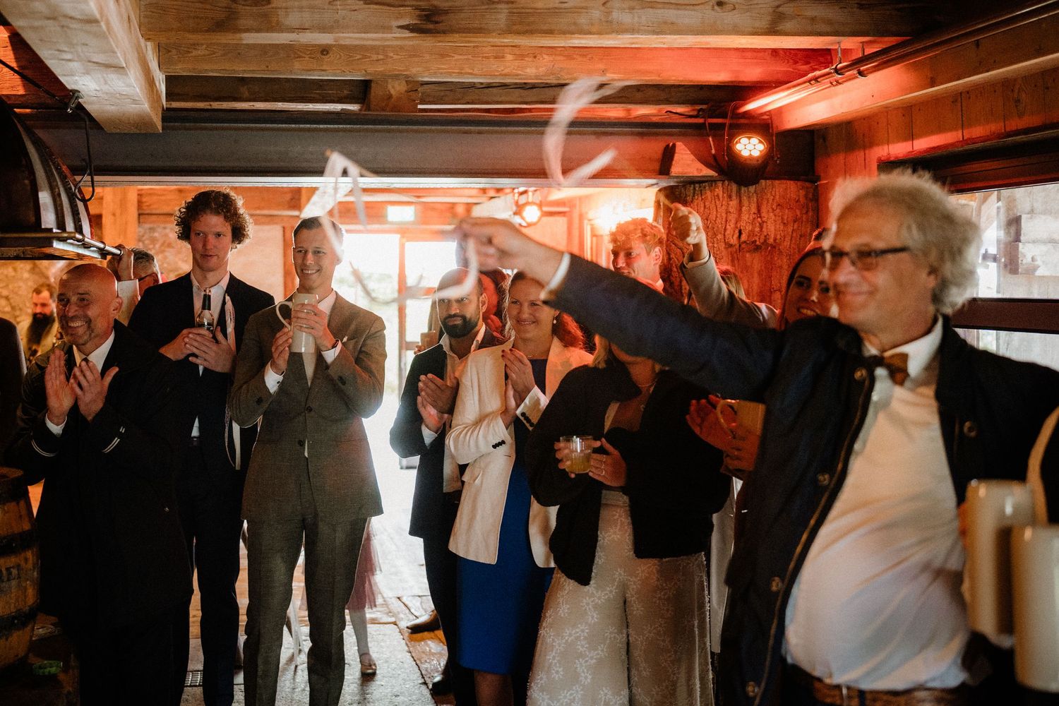 Wedding celebration in a barn with dramatic red lighting and dancing guests.