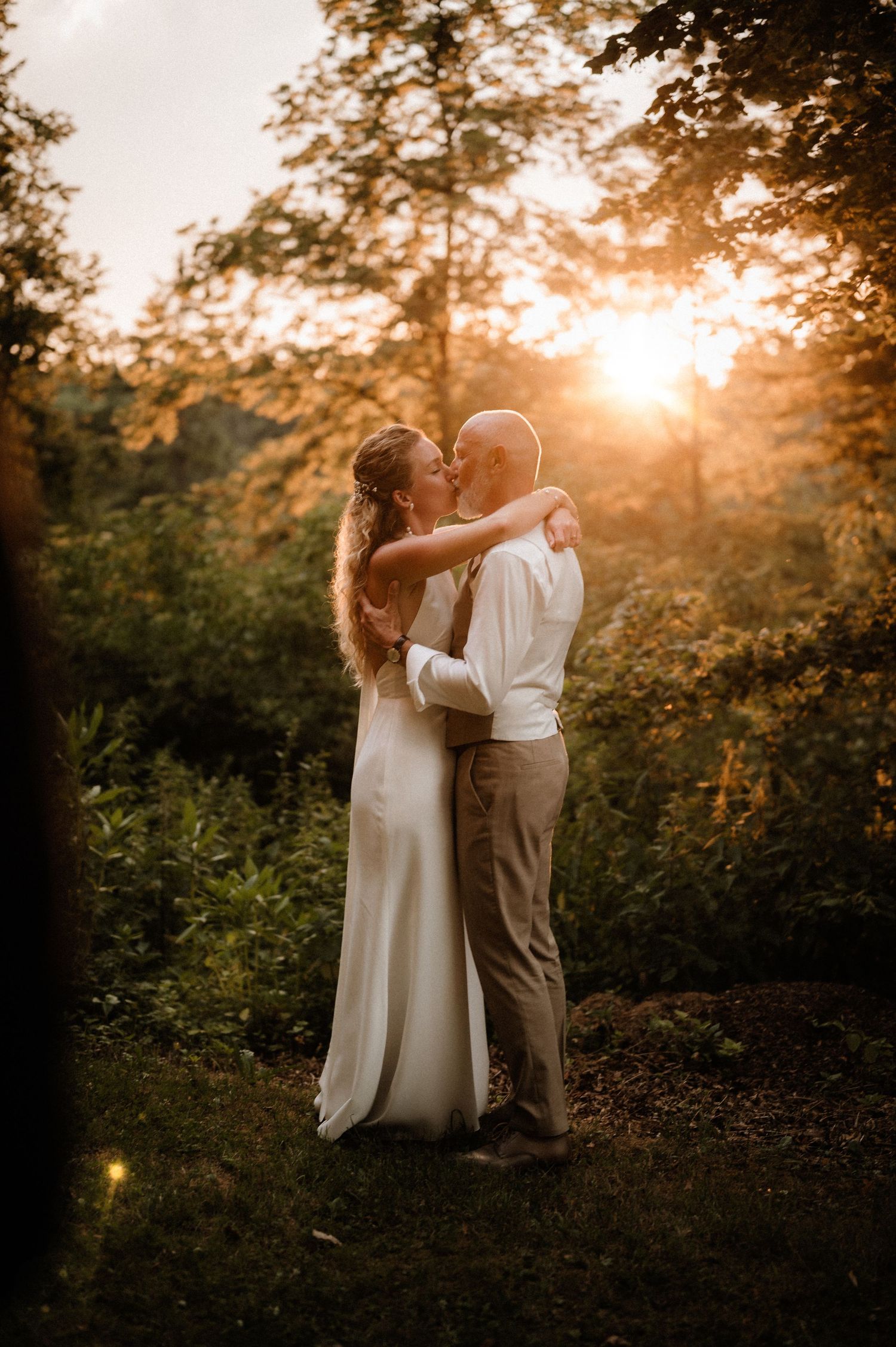 Warm sunset light illuminates a couple's intimate moment during their wedding photoshoot.