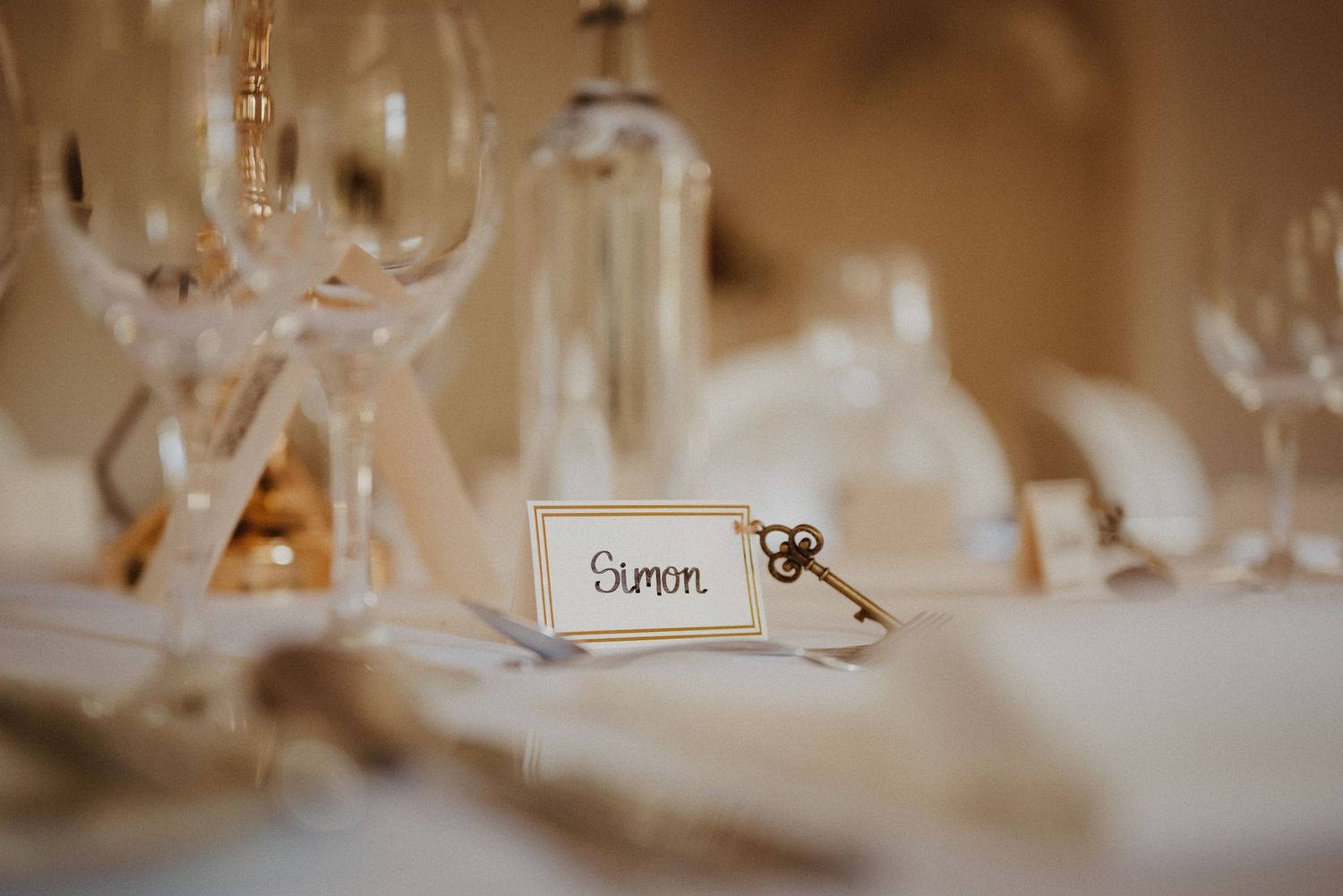 Close-up detail shot of wedding place cards and table settings in warm lighting.