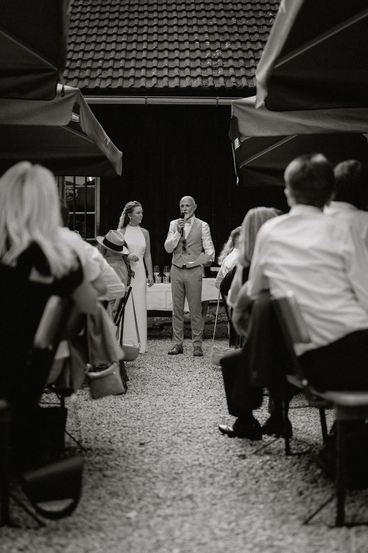 Black and white shot of guests seated at an outdoor reception venue.