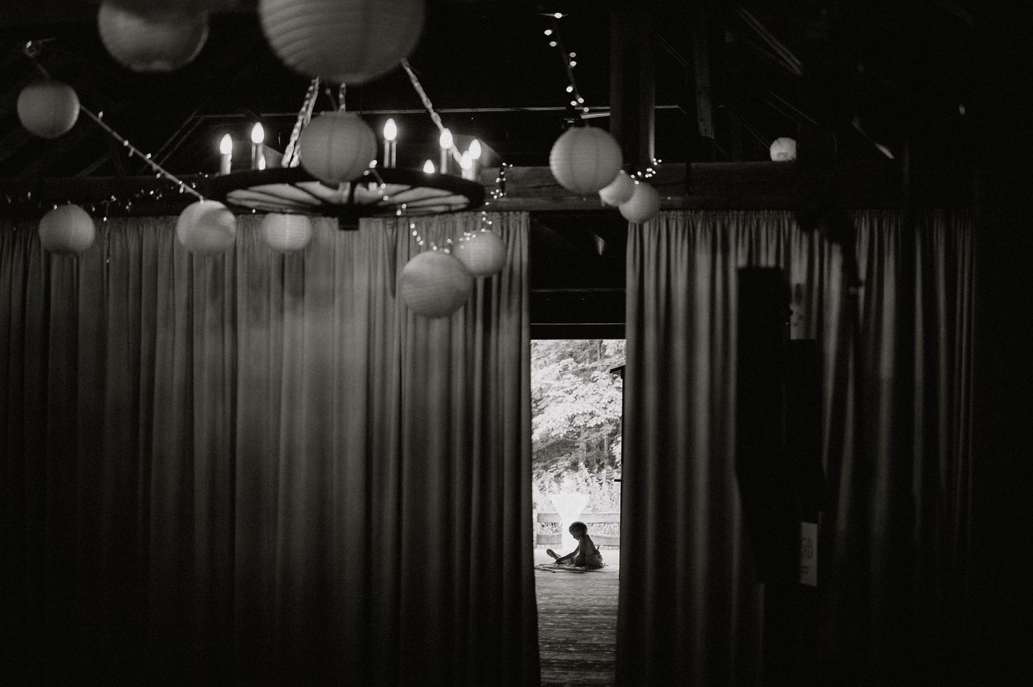 Dimly lit barn venue with paper lanterns and string lights creating ambient atmosphere.