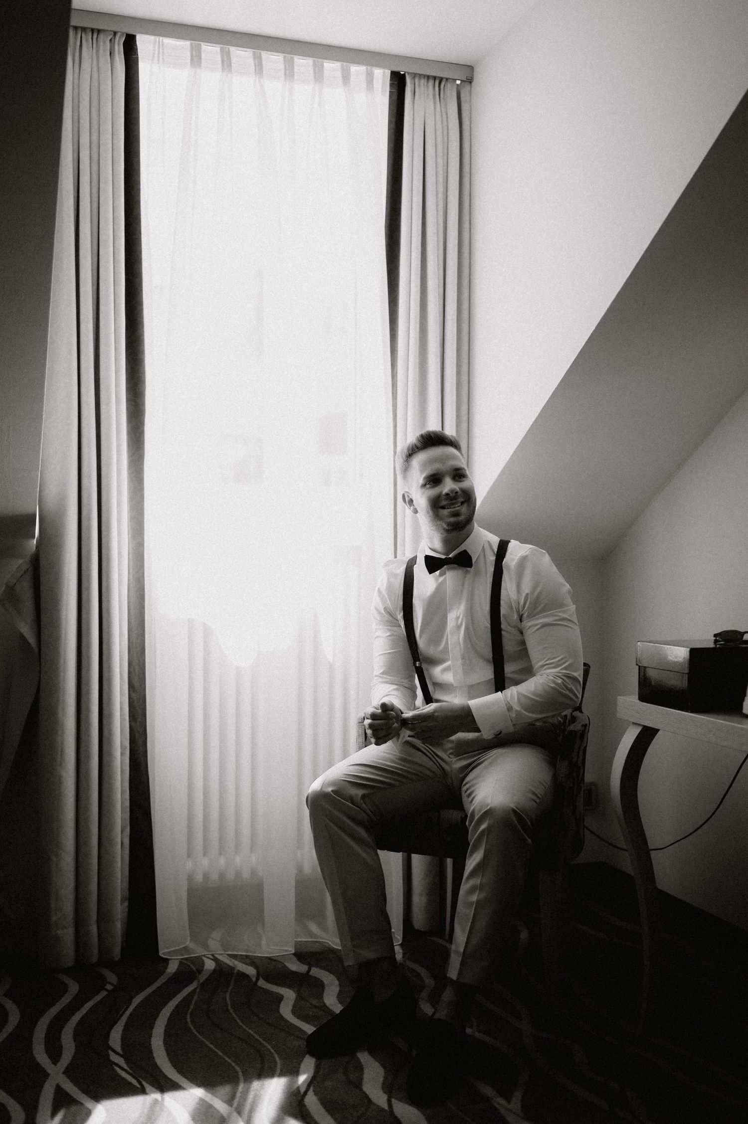 Black and white photograph of formal attire in a sunlit hotel room.