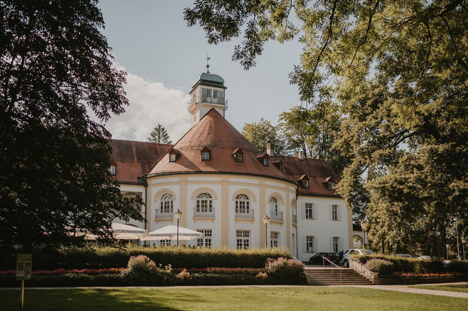 Panoramic view of an elegant white mansion with classical architecture and manicured grounds.