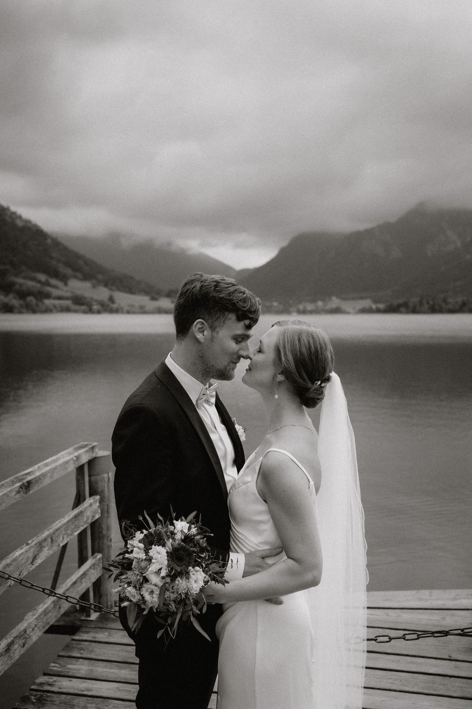 Intimate moment captured on wooden dock with misty mountain lake backdrop.