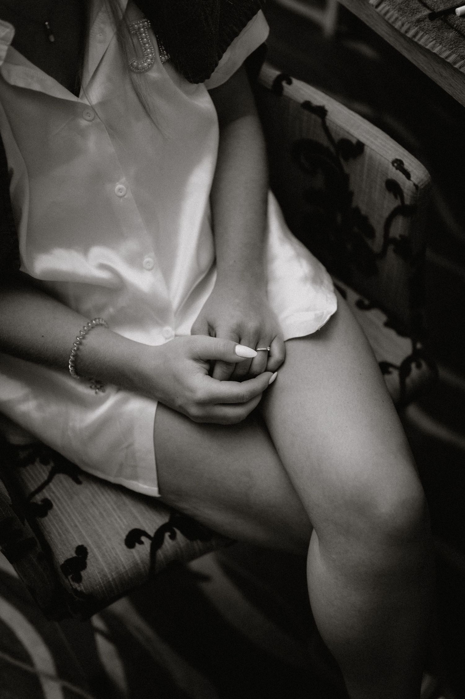 Black and white photo of someone in white satin clothing sitting down.