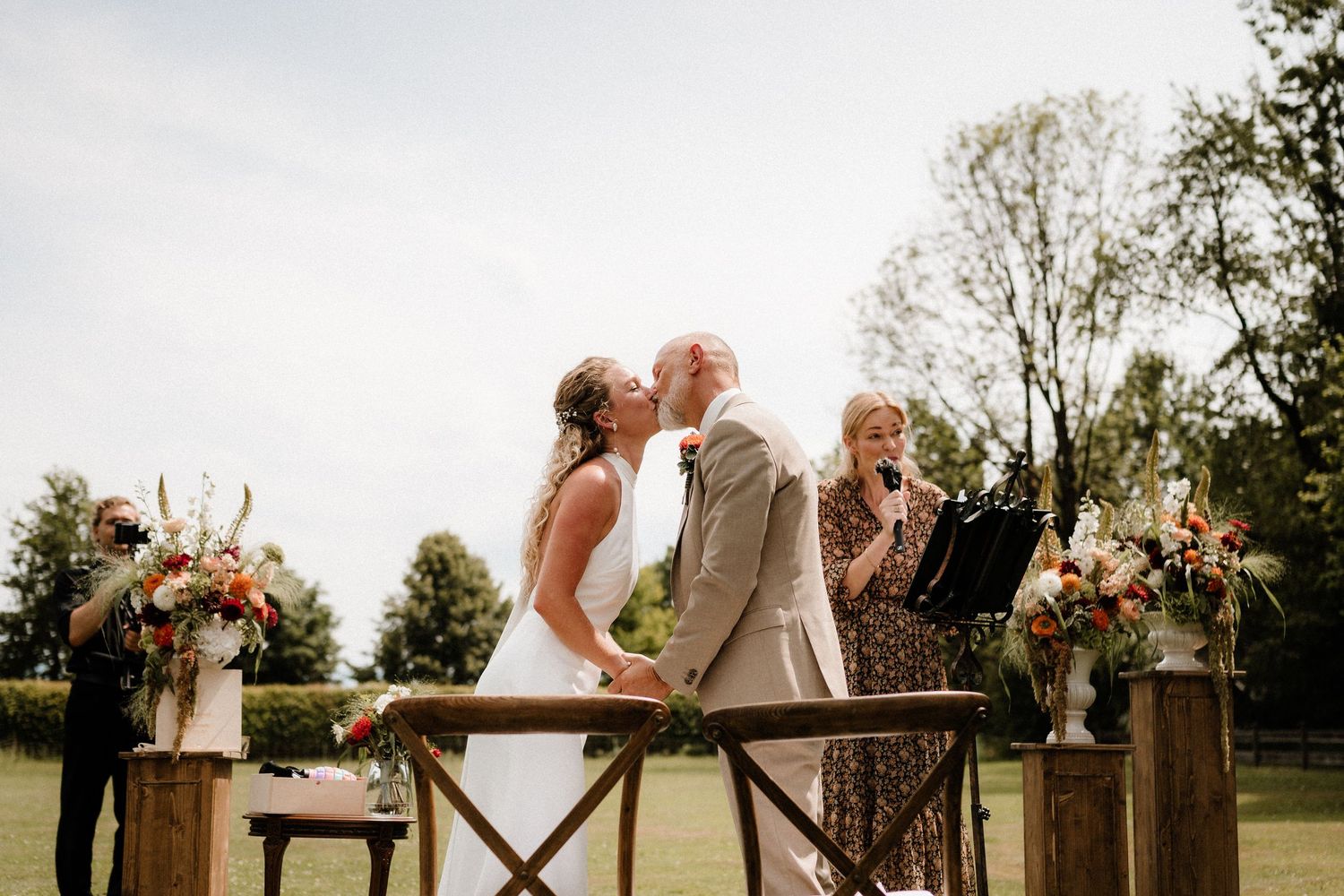 Panoramic view of an outdoor wedding celebration with a rustic barn in the background.