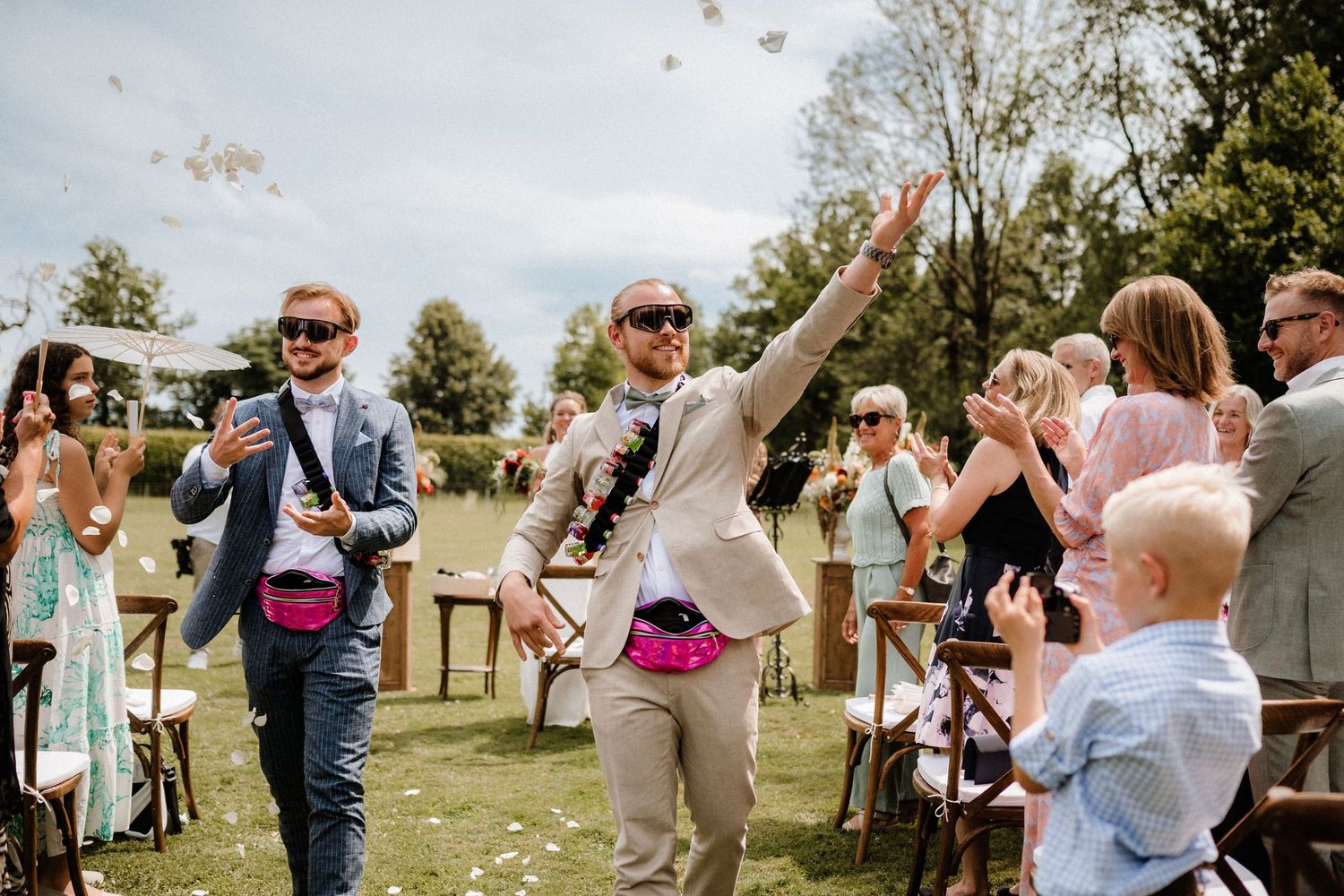 Wedding guests celebrate with raised arms during an outdoor summer celebration.