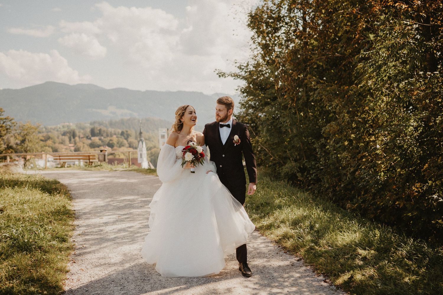 Wedding couple walking along a scenic mountain path during golden hour.