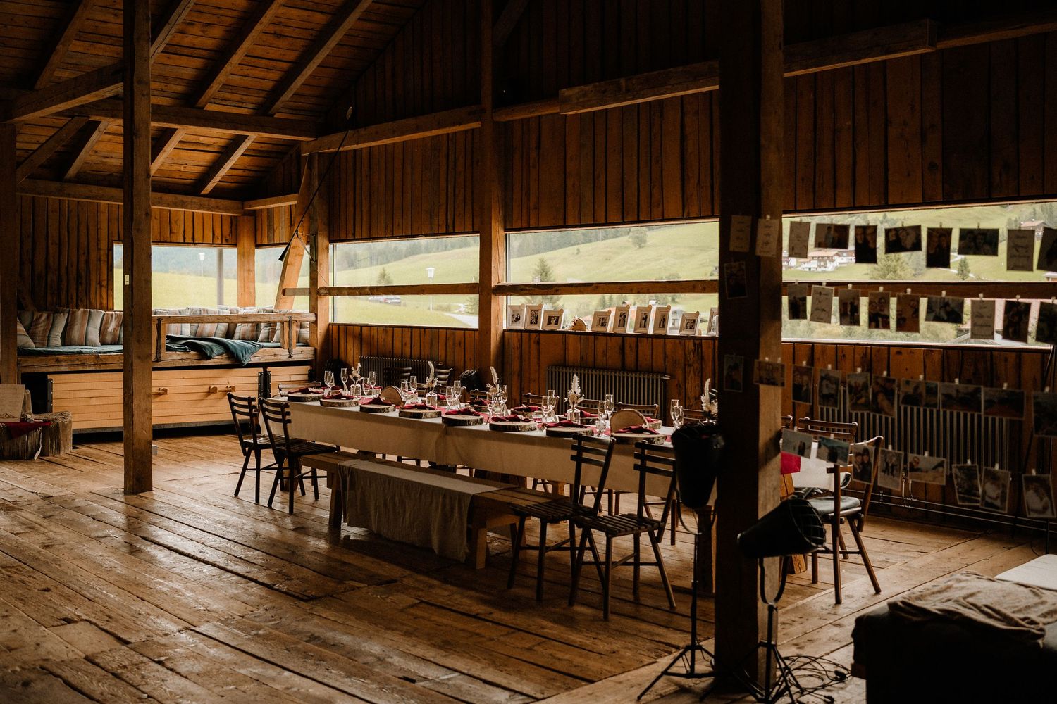 Long wooden benches and tables line the interior of a rustic dining hall with exposed wooden beams and paneled walls.