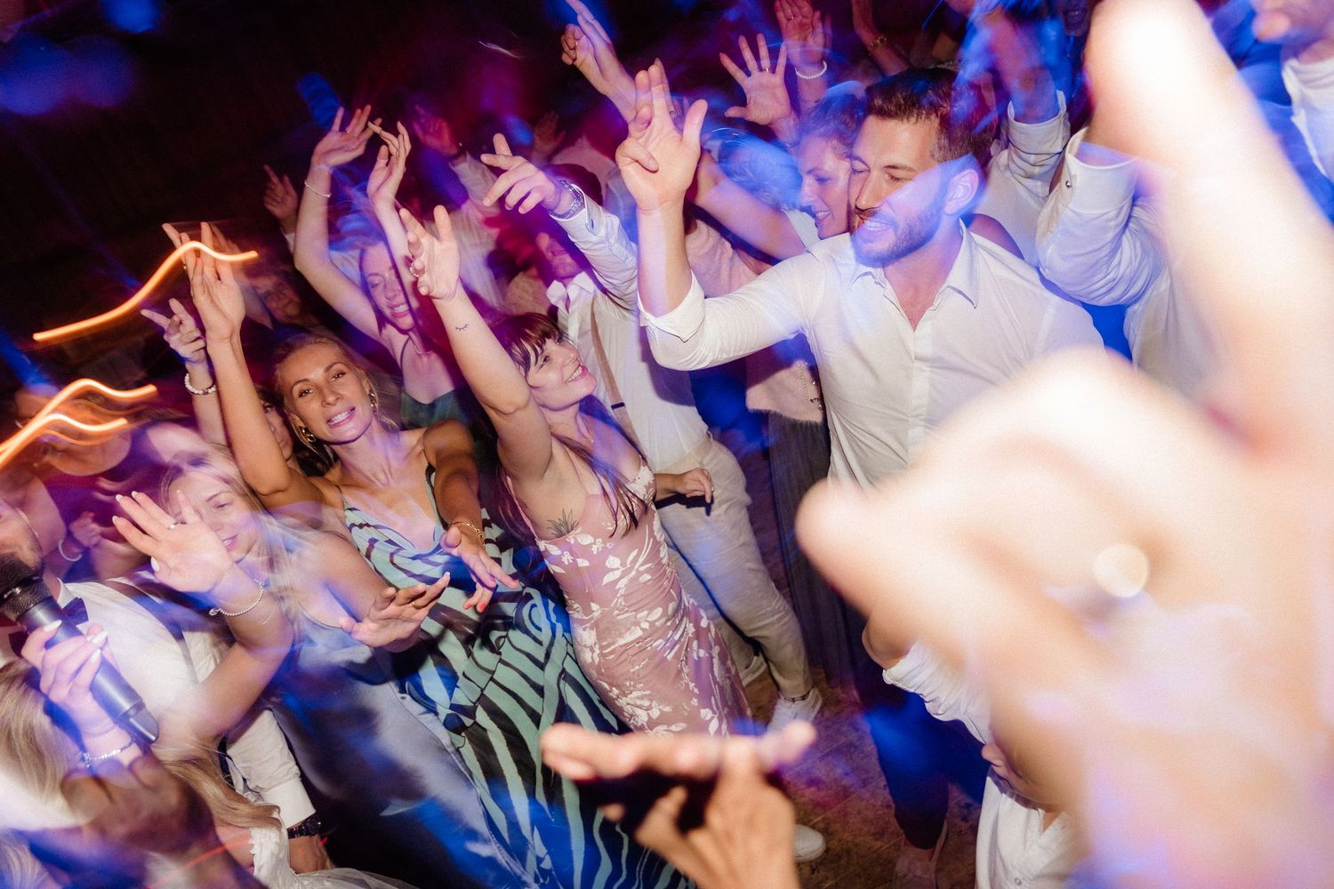 Blurred motion shot of people dancing and celebrating at a nightclub event.