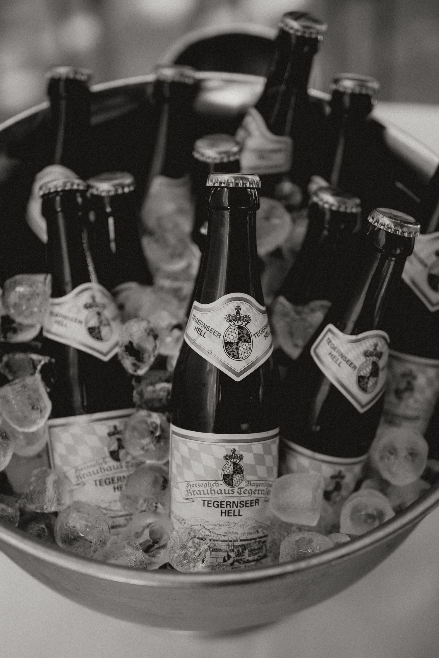 Black and white photo of beer bottles chilling in ice at a wedding reception.