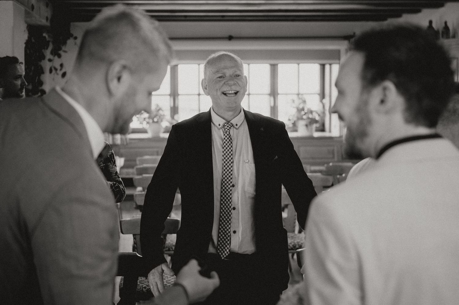 Three wedding guests share a lighthearted moment during an indoor celebration.