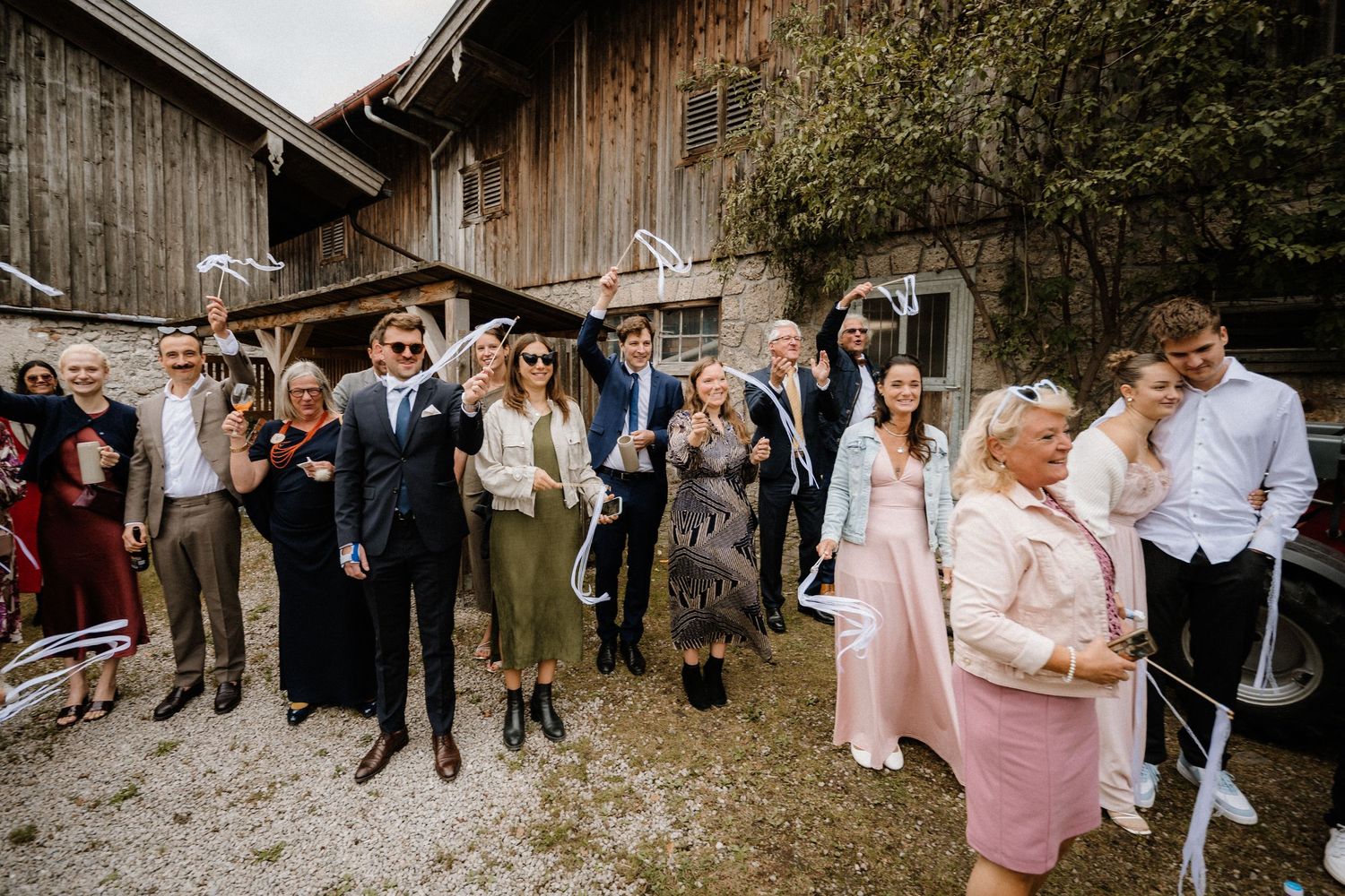 Wedding guests gathered outside a rustic wooden barn celebrate during the reception.