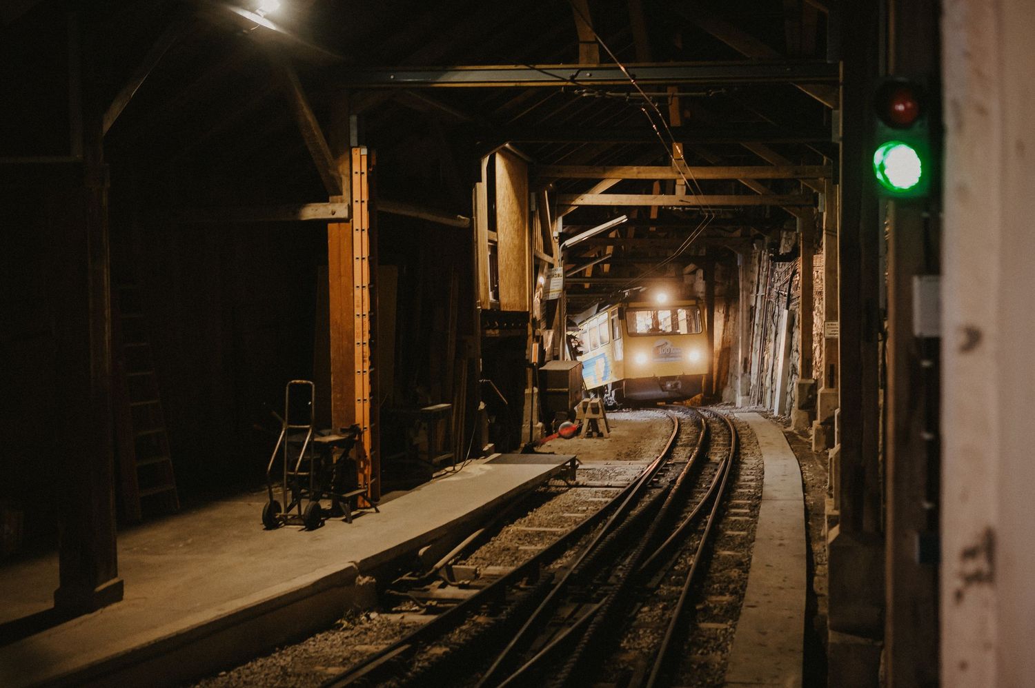 Dark railway station platform with tracks and lighting creating moody atmosphere.