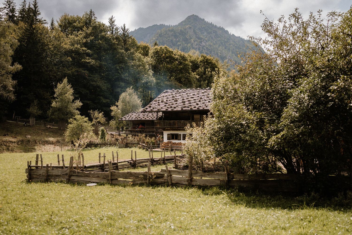 Panoramic view of rustic mountain cabins scattered across a green pastoral landscape.