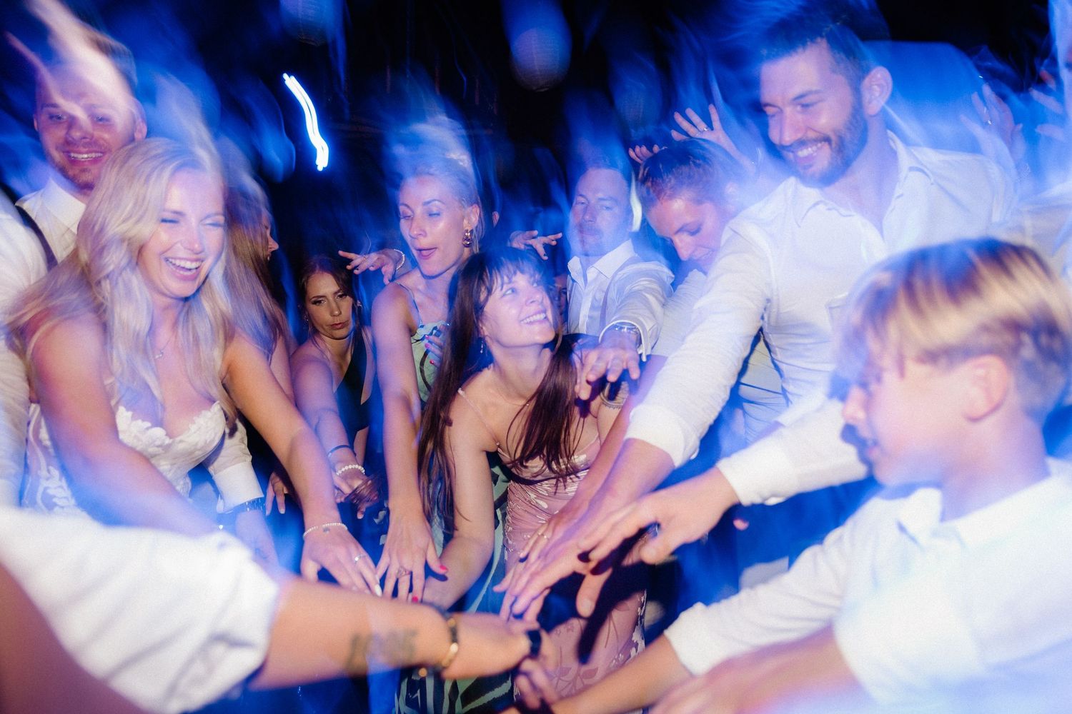 Energetic crowd dancing and celebrating at a nightclub under blue lighting.
