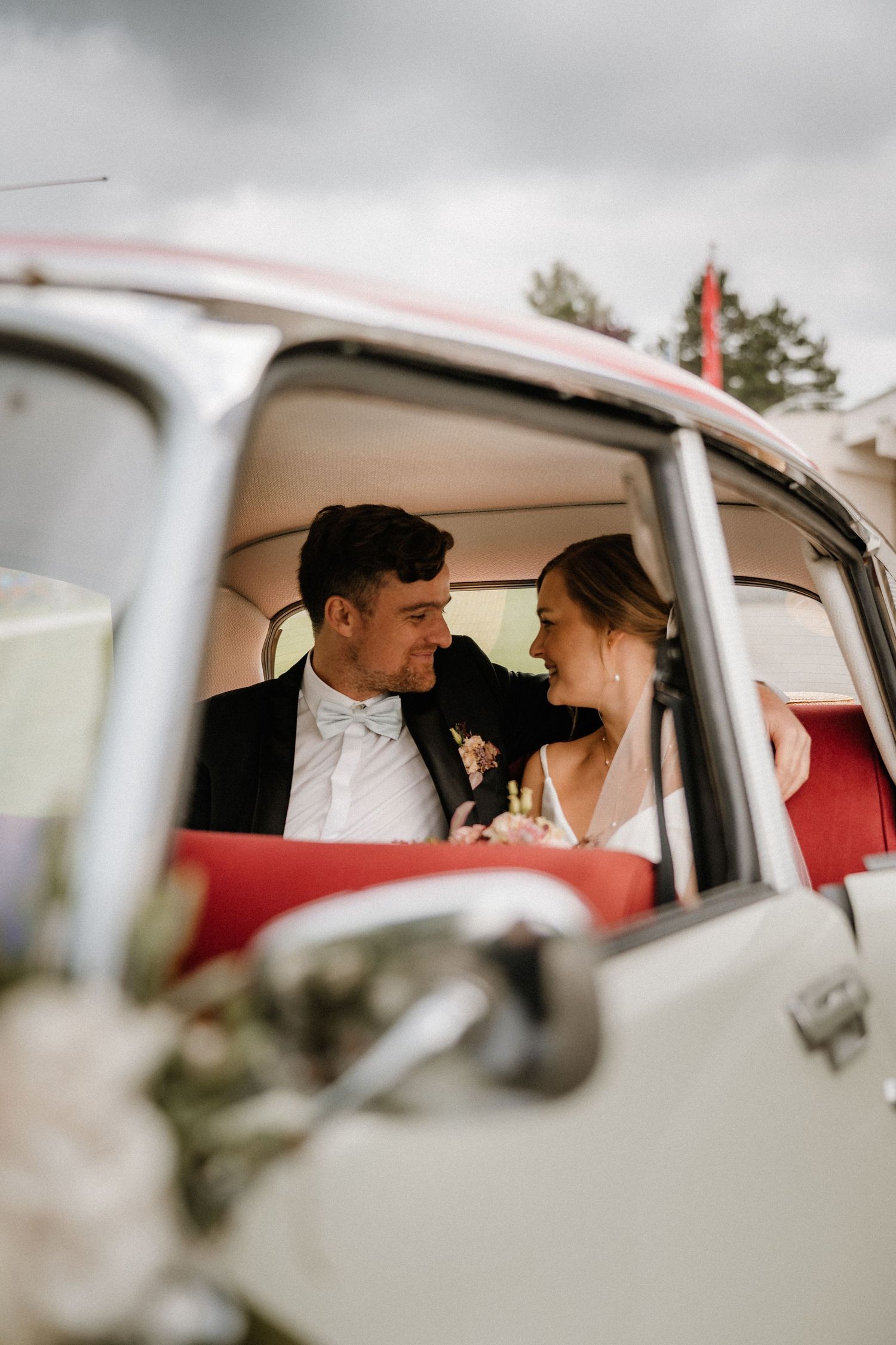 Intimate moment captured through vintage car windows with red interior.