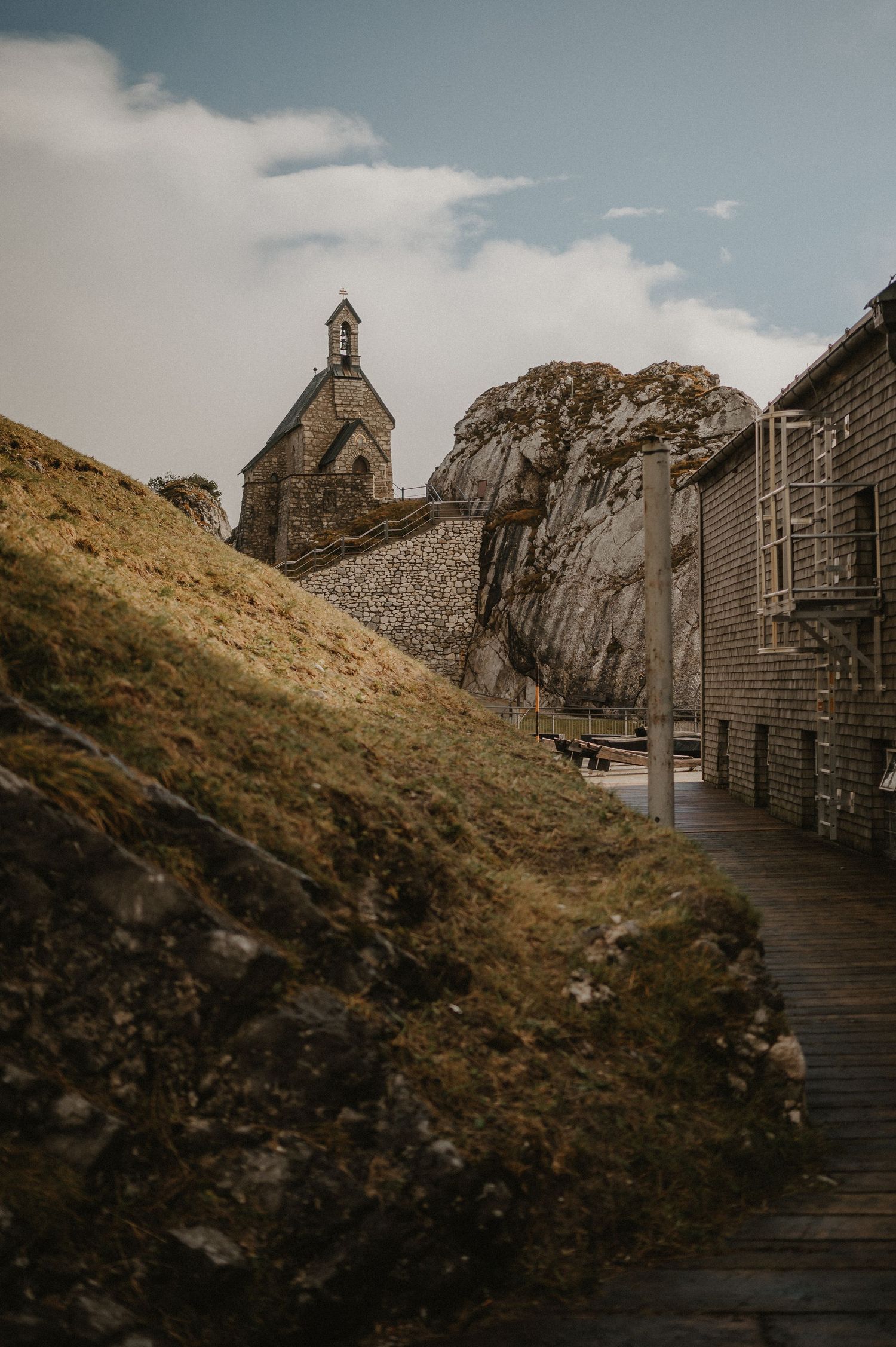Stone buildings and wooden walkways along a rugged mountain ridge path.