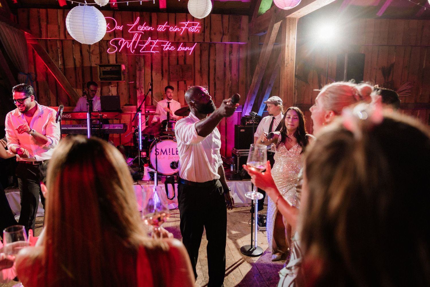 Wedding reception dance floor with band performing under paper lanterns and purple lighting.
