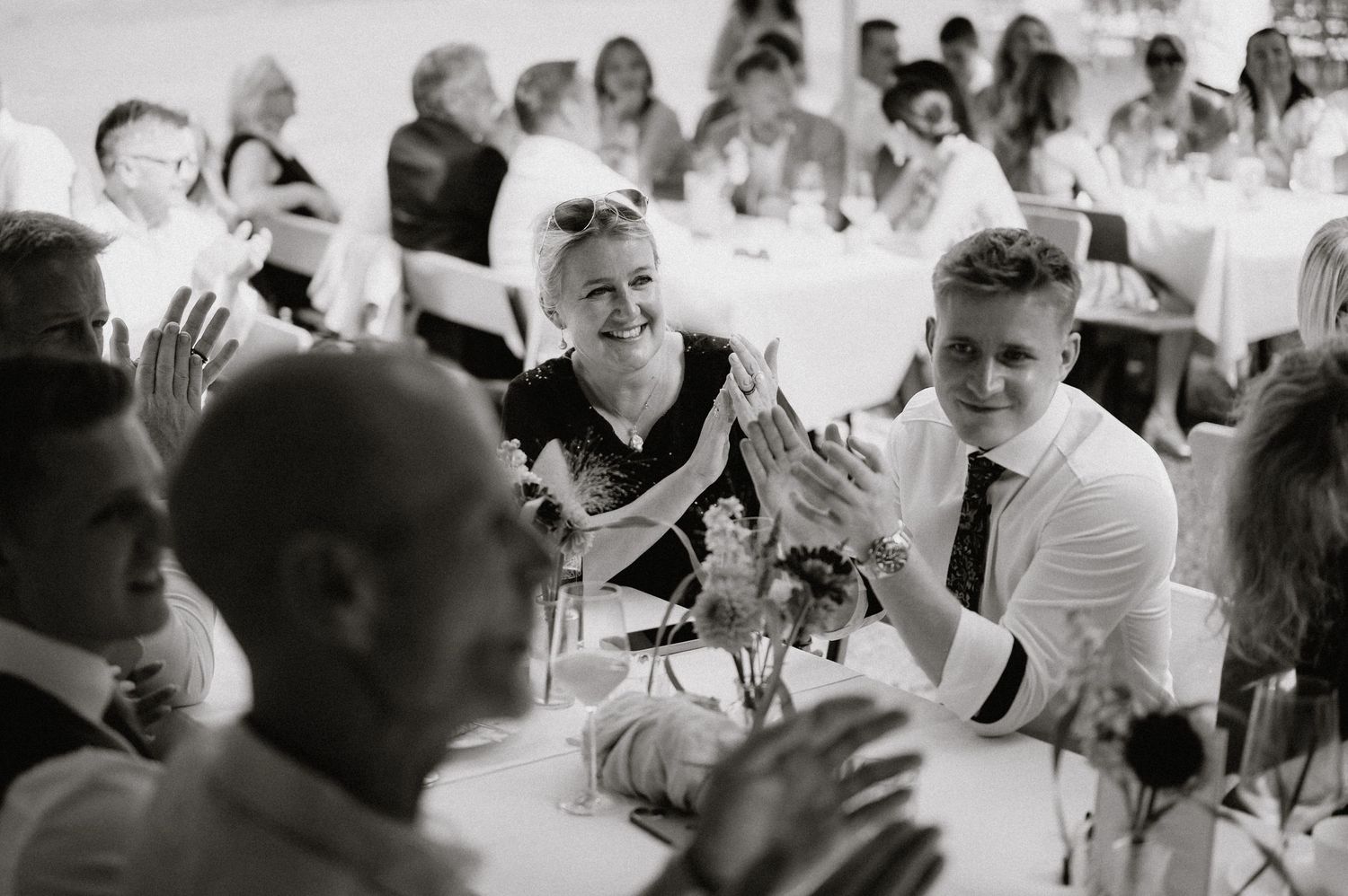 Wedding reception guests celebrate with raised hands and smiles during a festive moment.