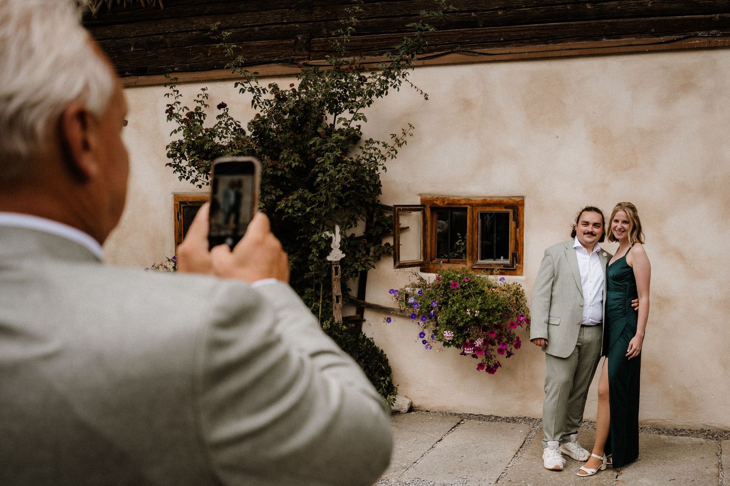 Rustic outdoor wedding venue with stone walls and wooden beams decorated with floral arrangements.