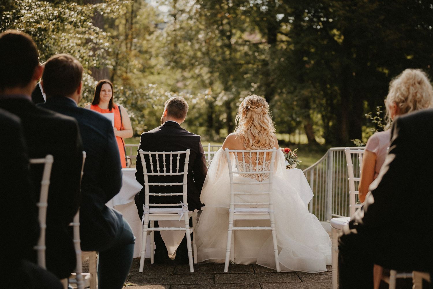 Sunlit outdoor wedding venue with white chairs arranged in rows for ceremony guests.